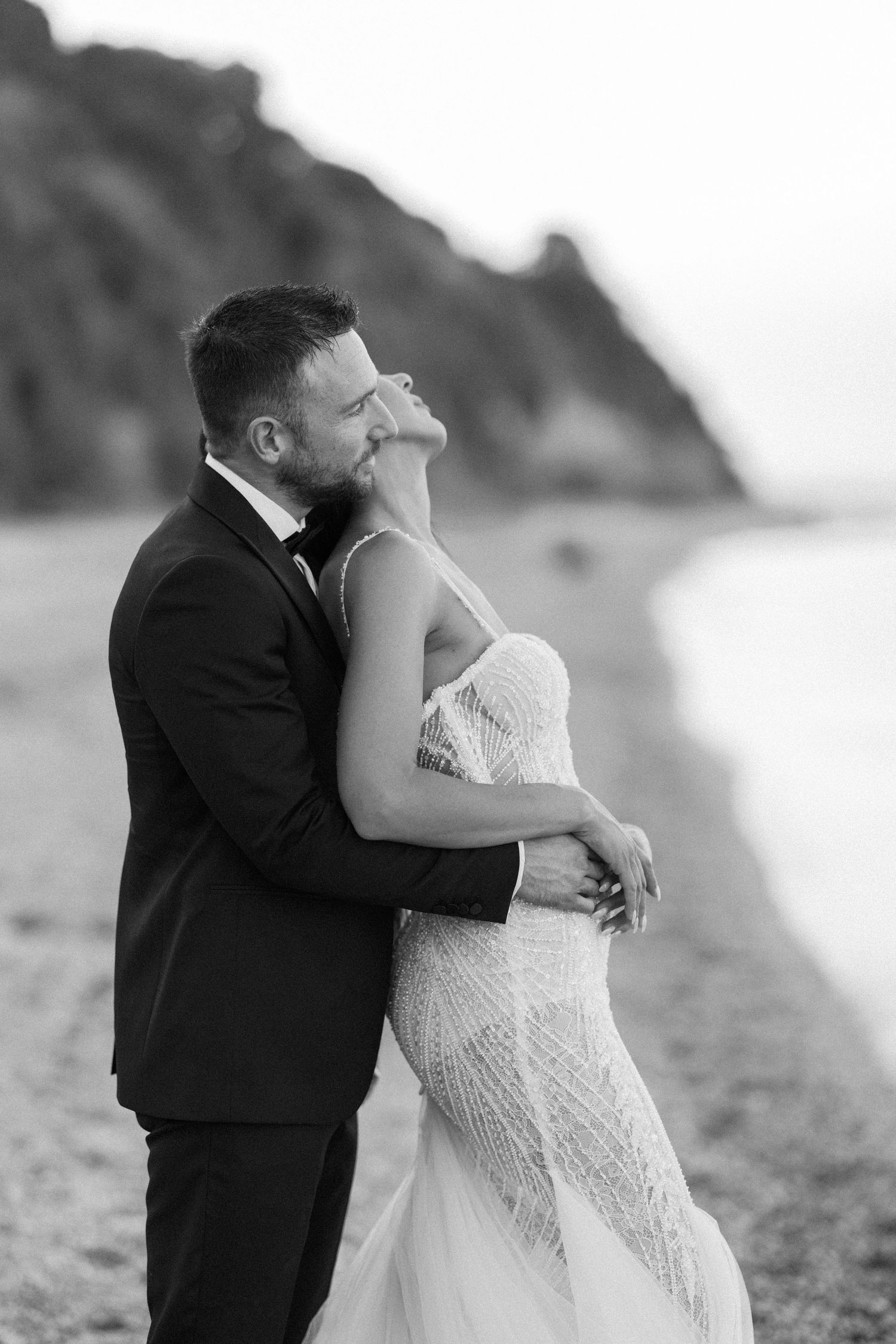 Romantic black and white beach wedding photos showing intimate moments between newlyweds at sunset.