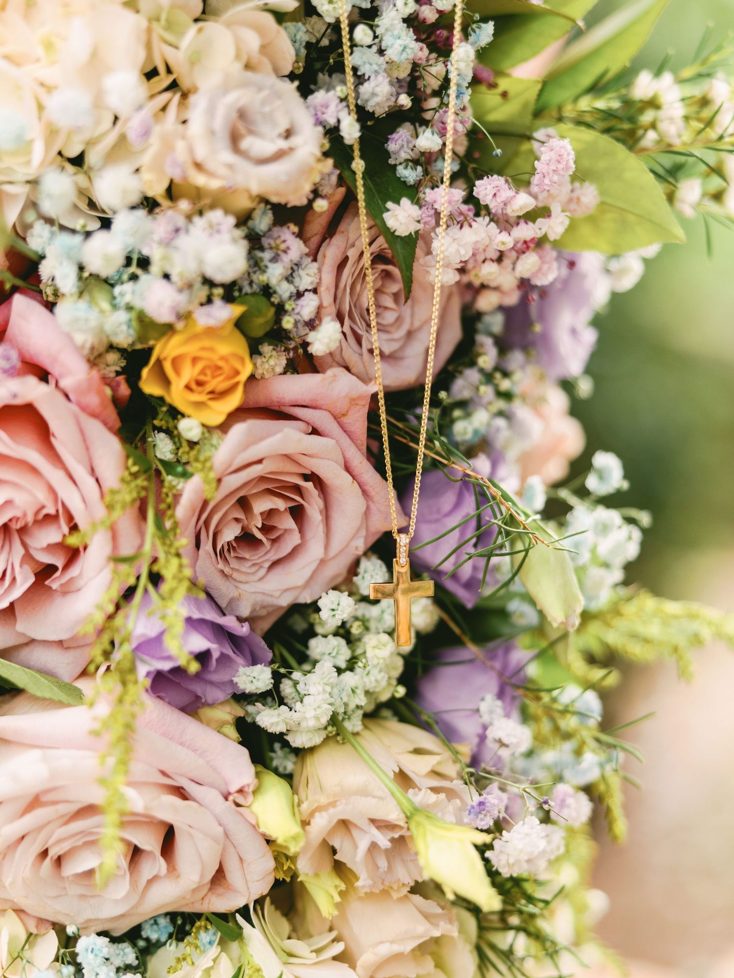 Close-up of a romantic wedding bouquet with pink roses, purple flowers and baby's breath against a soft blurred background.