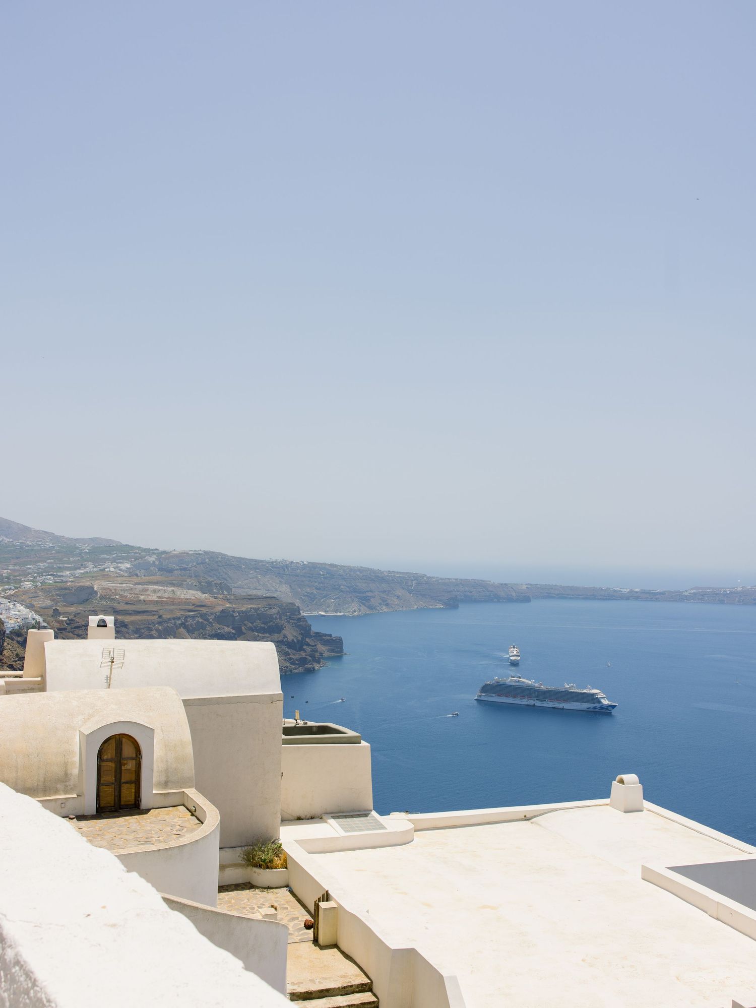 White architecture and buildings overlooking the Mediterranean Sea with a cruise ship in the distance.