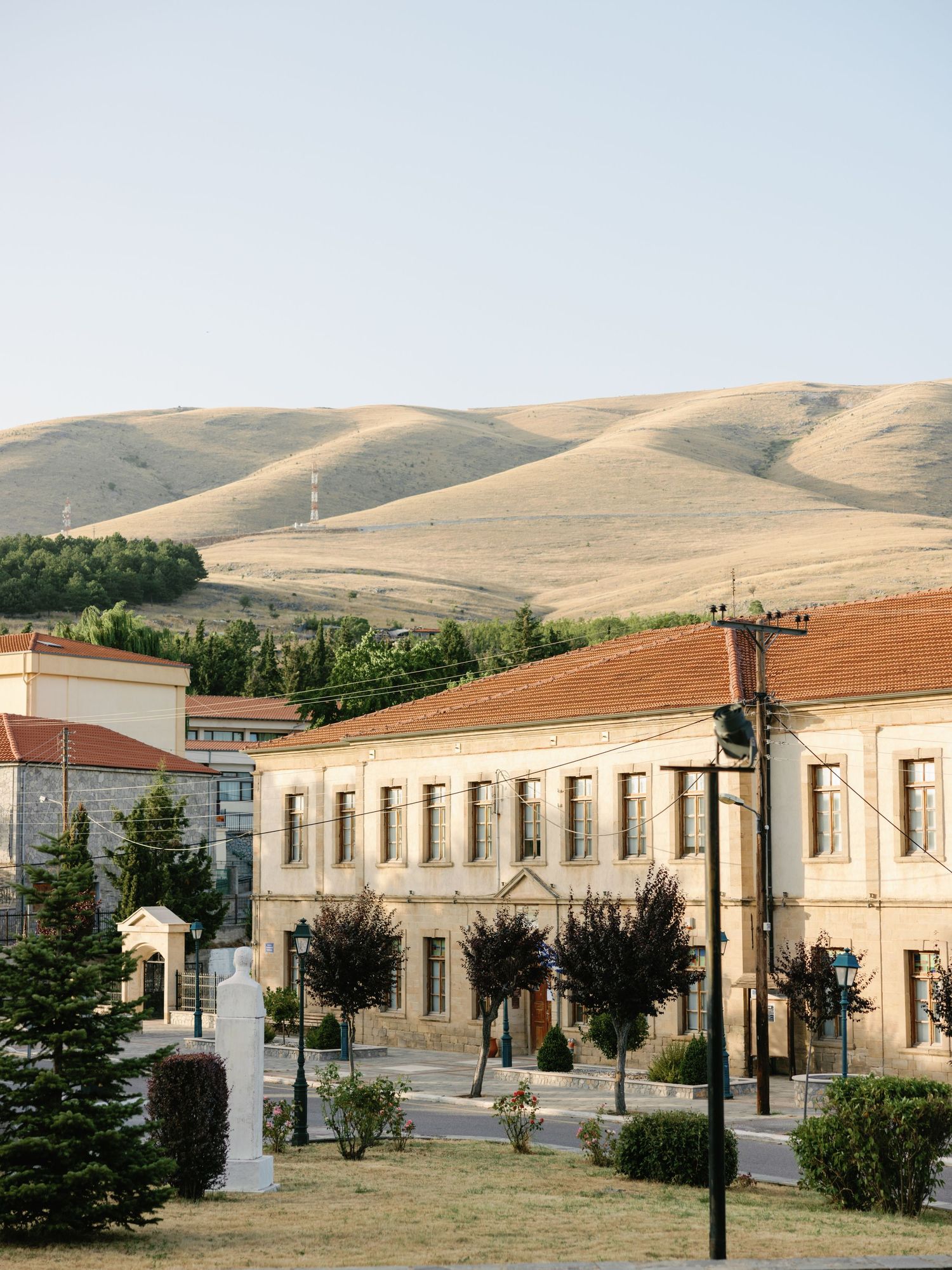 Historic town buildings nestled against rolling golden hills with sparse vegetation.