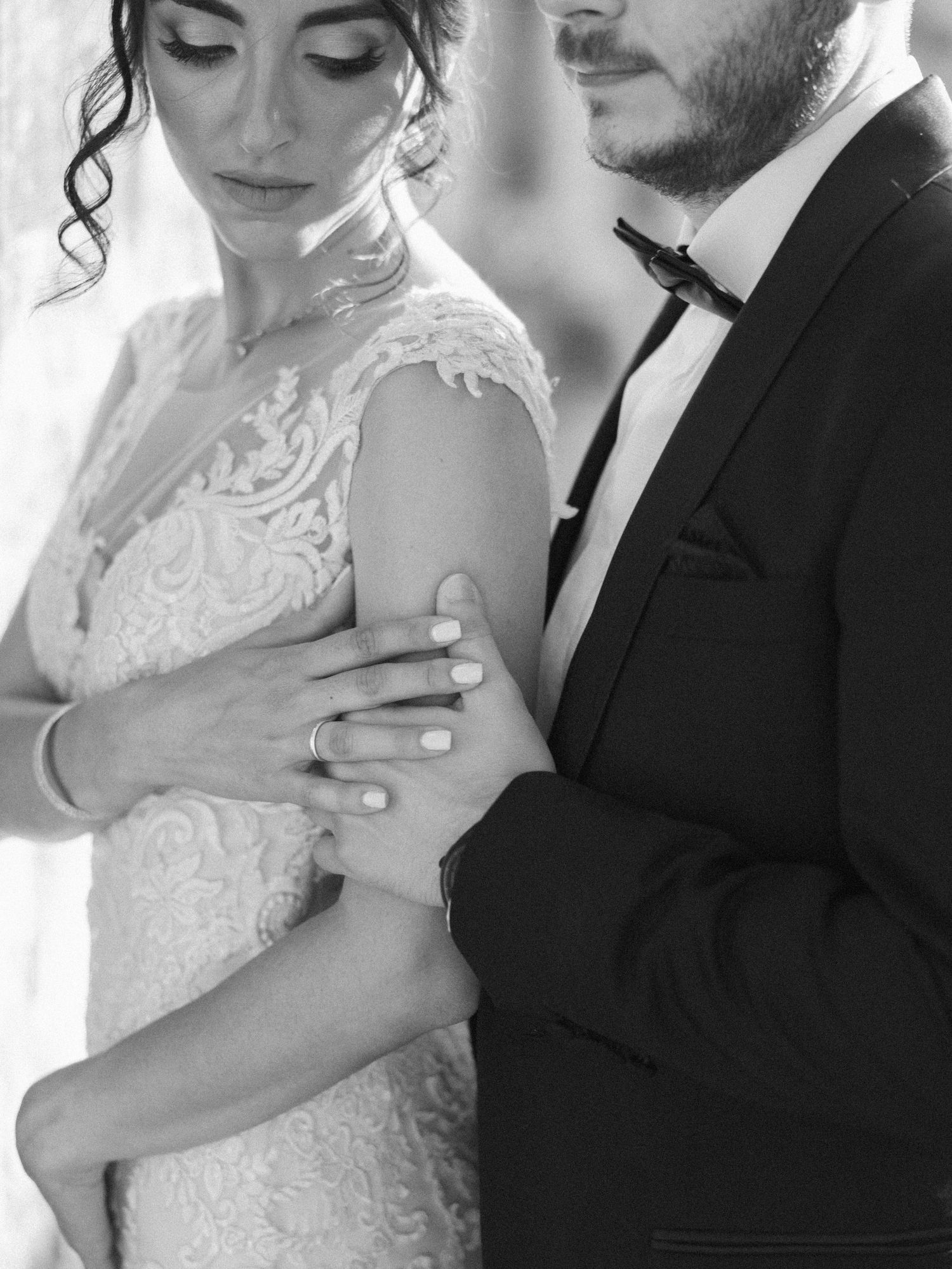 Black and white close-up of wedding couple showing intricate lace dress details.