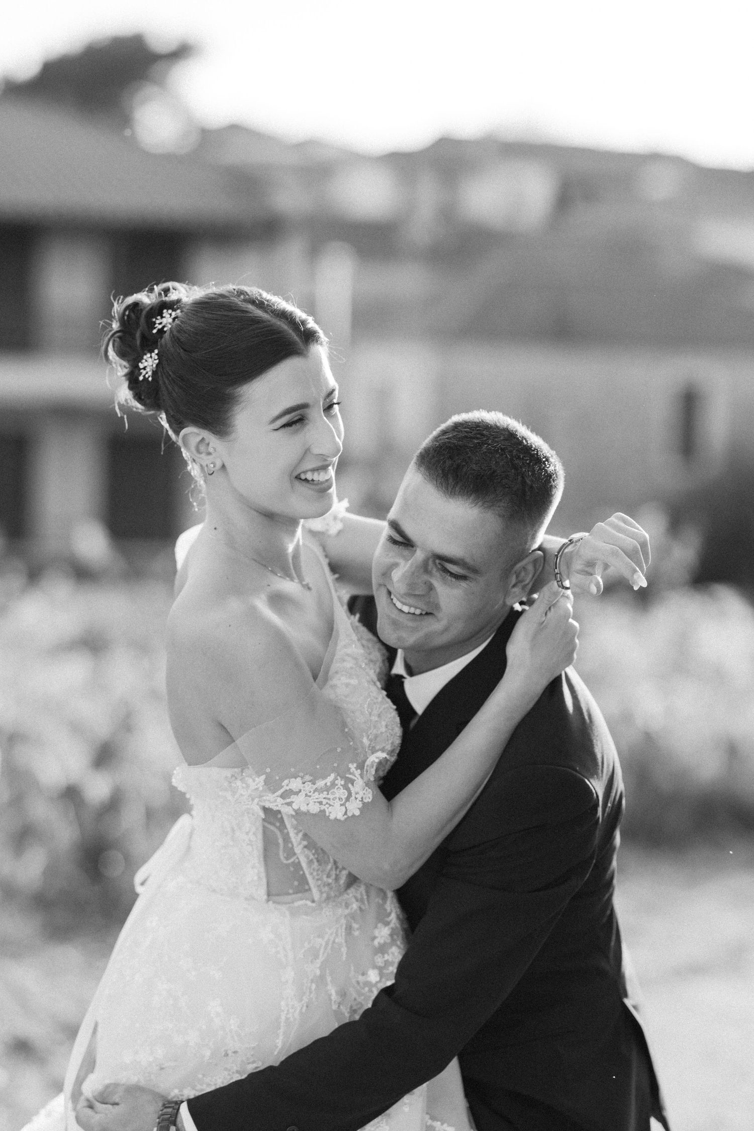Black and white portraits of newlyweds embracing and laughing together outdoors.