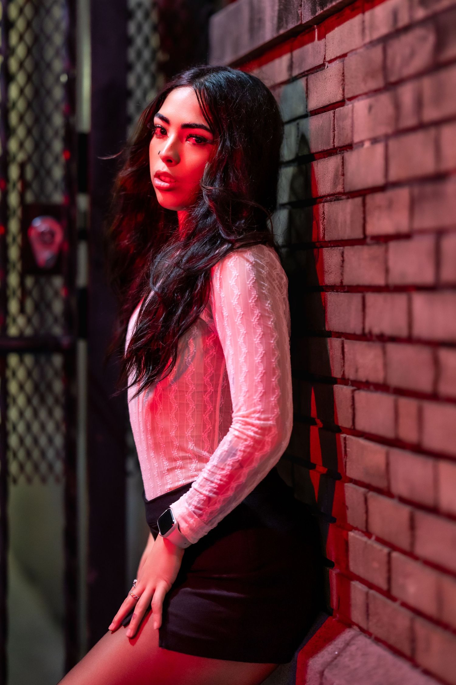 Artistic portrait series with dramatic red lighting against a brick wall backdrop.