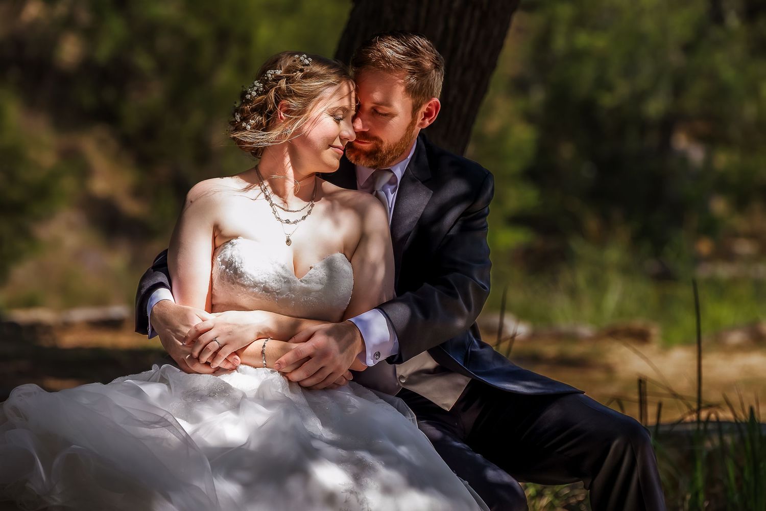 A romantic couple shares tender moments in an outdoor setting with natural sunlight filtering through the trees.