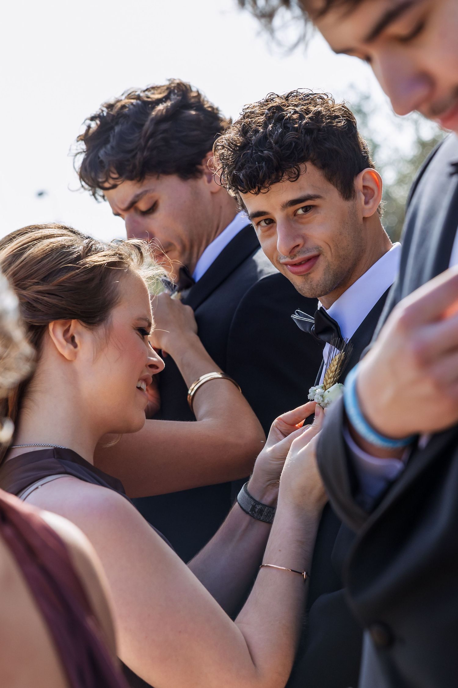 Wedding party members share an intimate moment during outdoor ceremony.