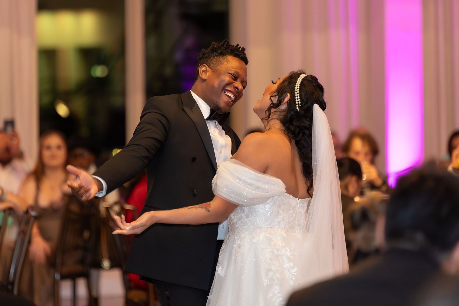 Romantic dance moments captured during an elegant wedding reception with pink lighting.