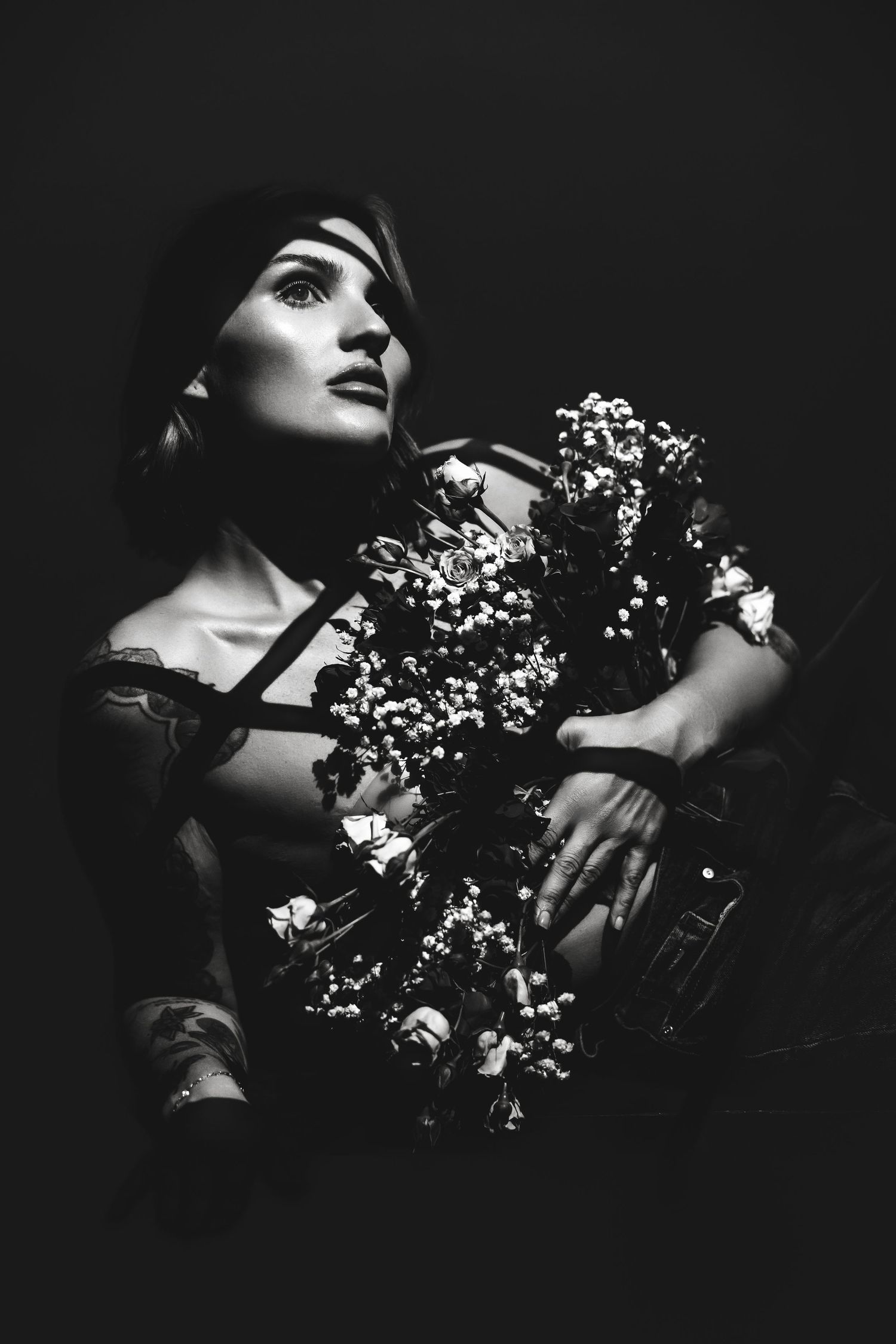 Dramatic black and white portrait with baby's breath flowers creating artistic shadows and light.