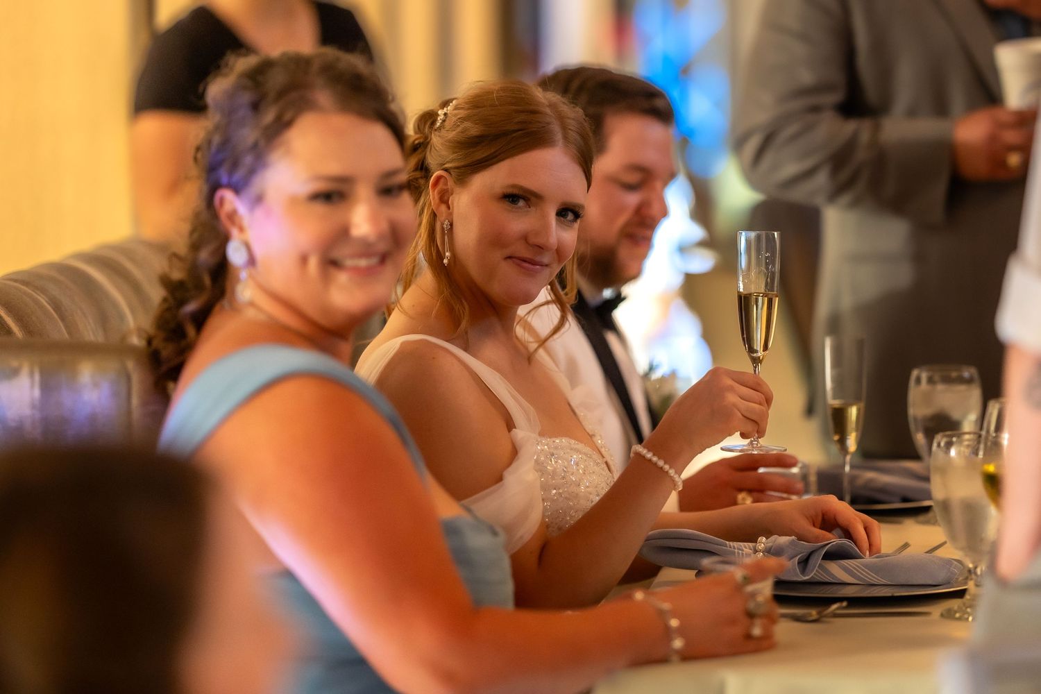 Wedding reception guests enjoying drinks and conversation at table.