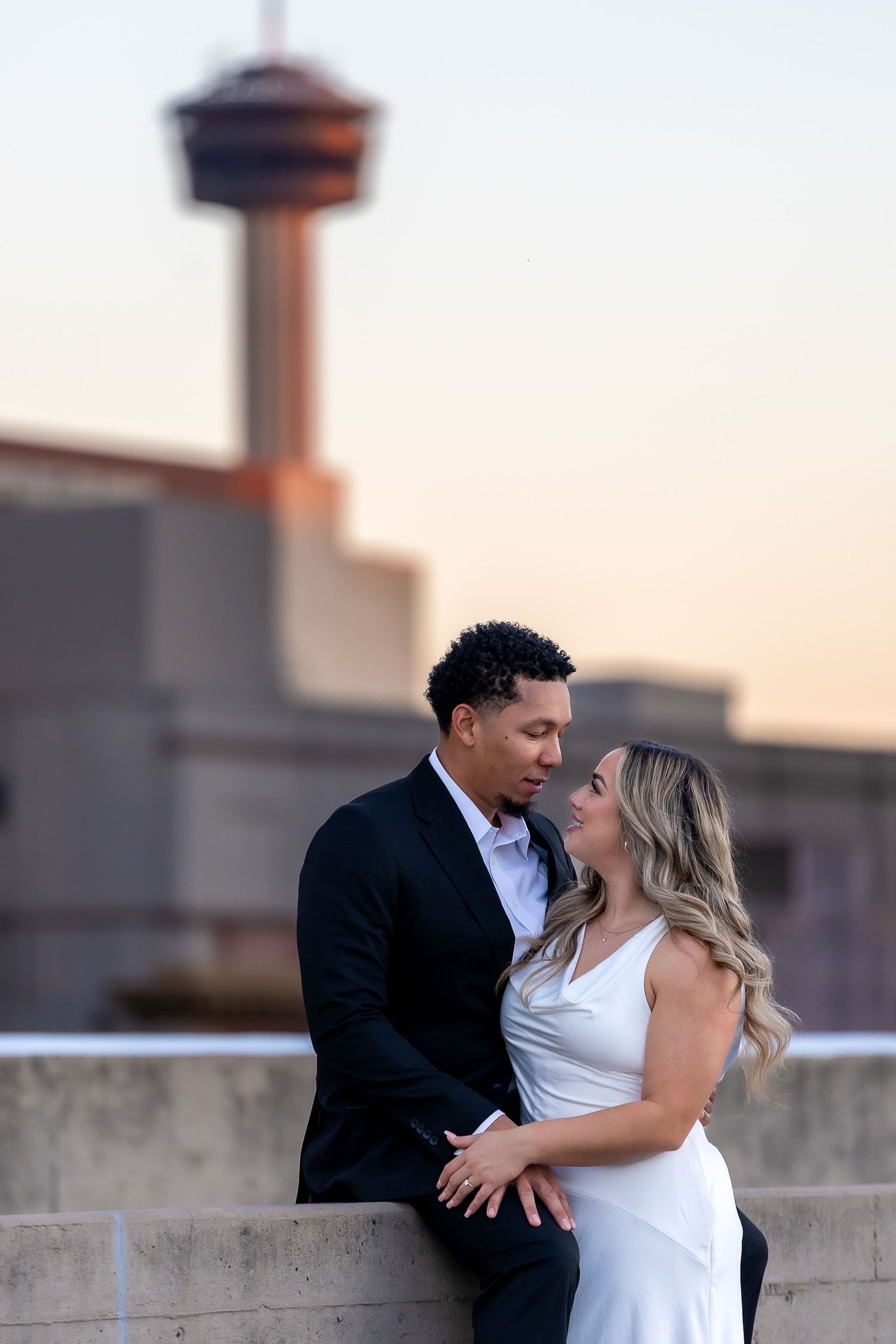 Couple shares romantic moment on rooftop during sunset photoshoot.