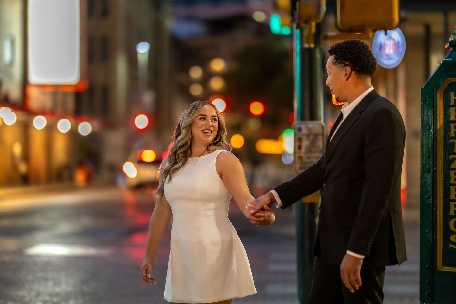Romantic nighttime dance on city street with glowing lights.