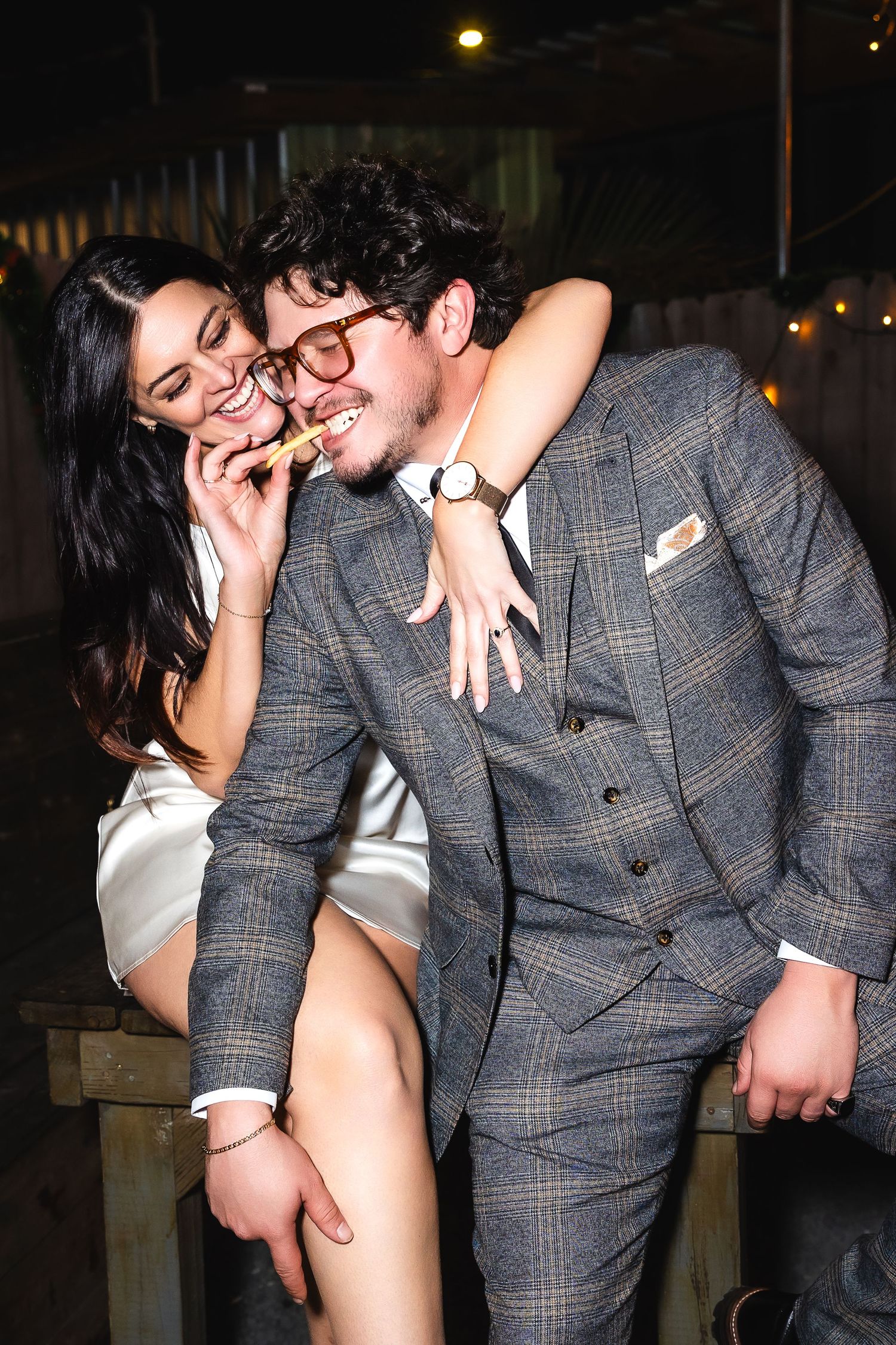 Couple sharing intimate moments in evening lighting, with one wearing a plaid suit.