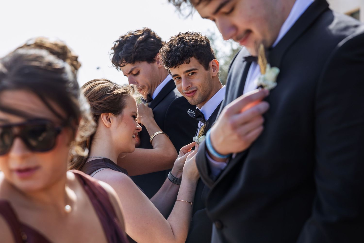 A group of formally dressed people looking down at their mobile phones during an event.
