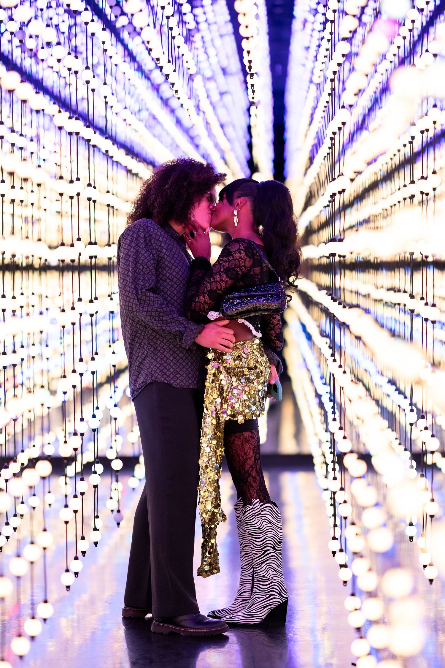 Couples silhouetted against a magical tunnel of purple string lights creating a dreamy effect.