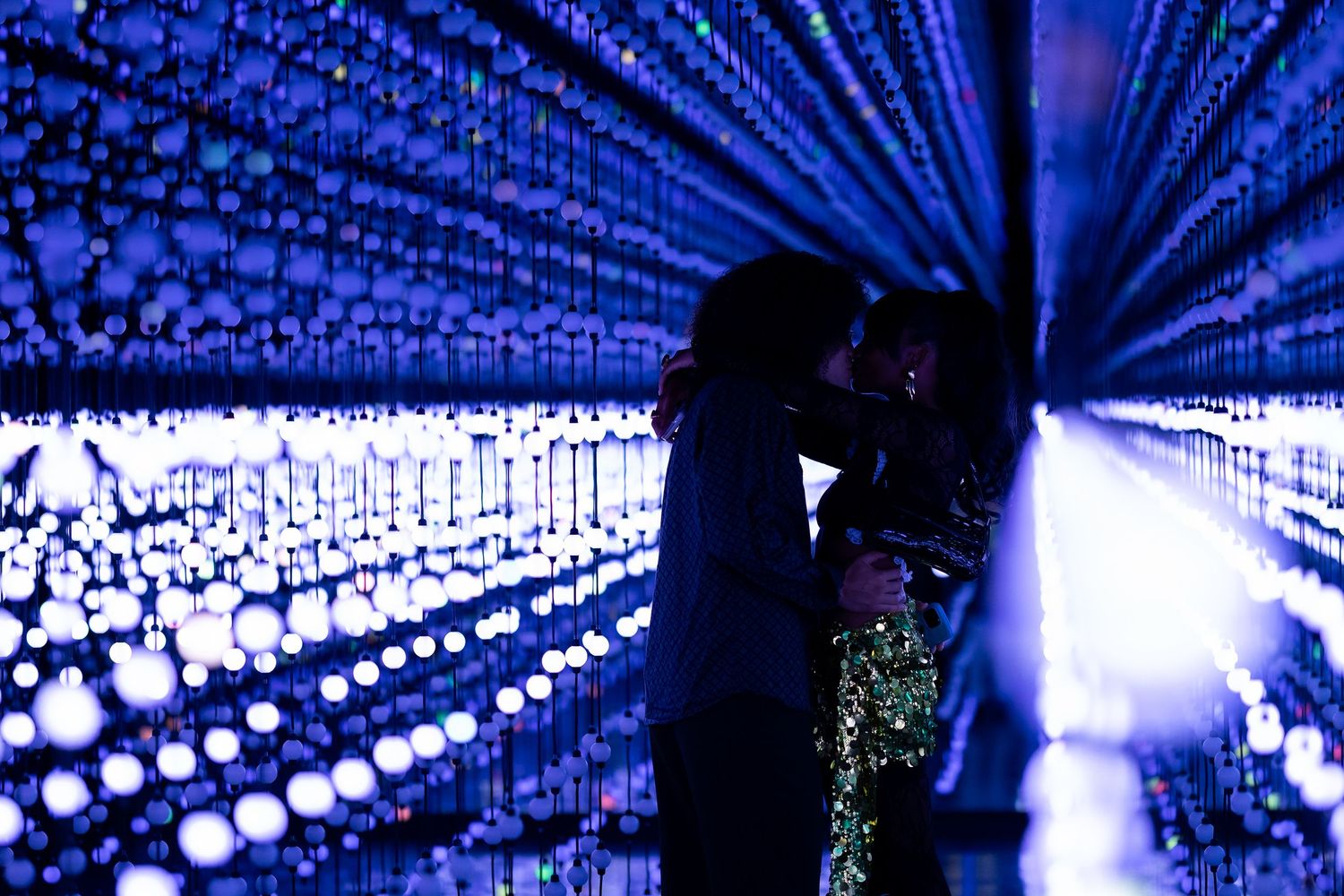 Romantic silhouettes against a backdrop of blue twinkling lights in a tunnel formation.