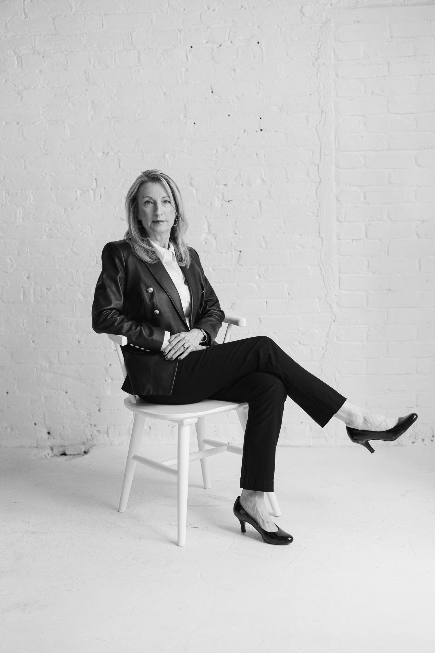 Black and white personal branding portrait of a business professional seated in a bright studio.