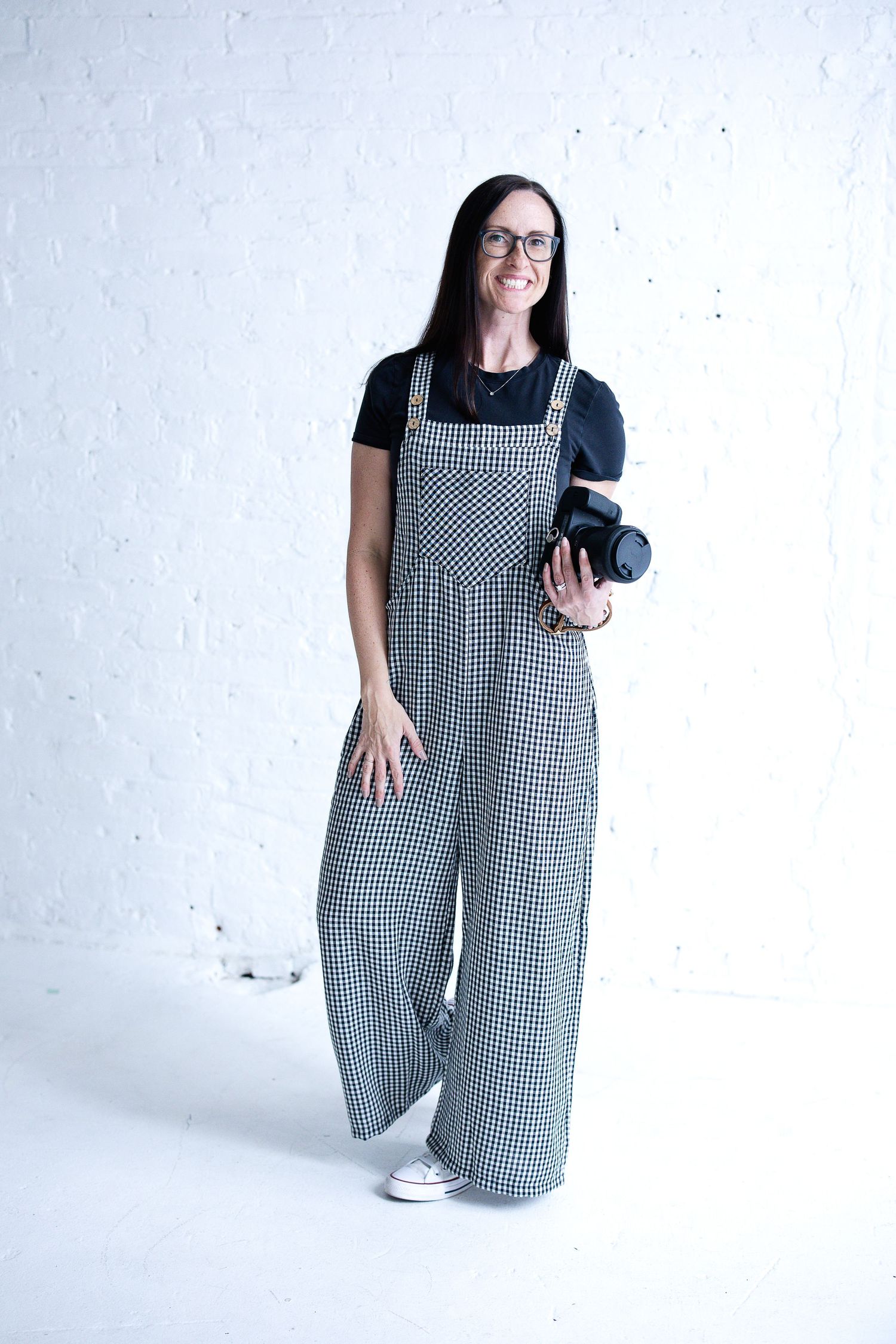 Katie Chamberlain, Tipp City and Dayton, Ohio photographer, holding her camera in a bright studio.
