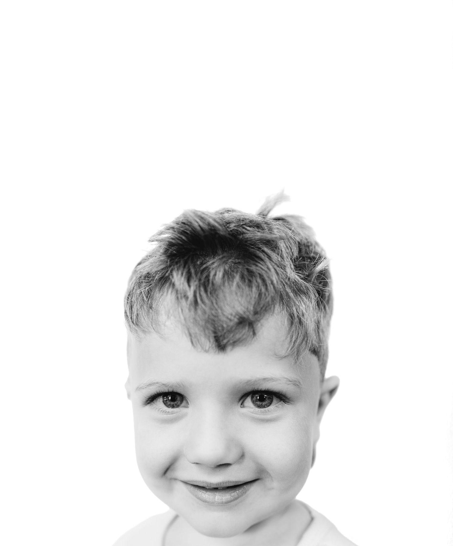 Black and white portrait of a smiling young boy with short hair against a white background.