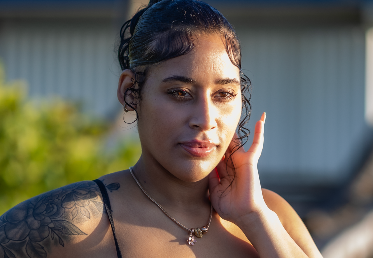 Woman poses outdoors during golden hour portrait session with natural lighting.