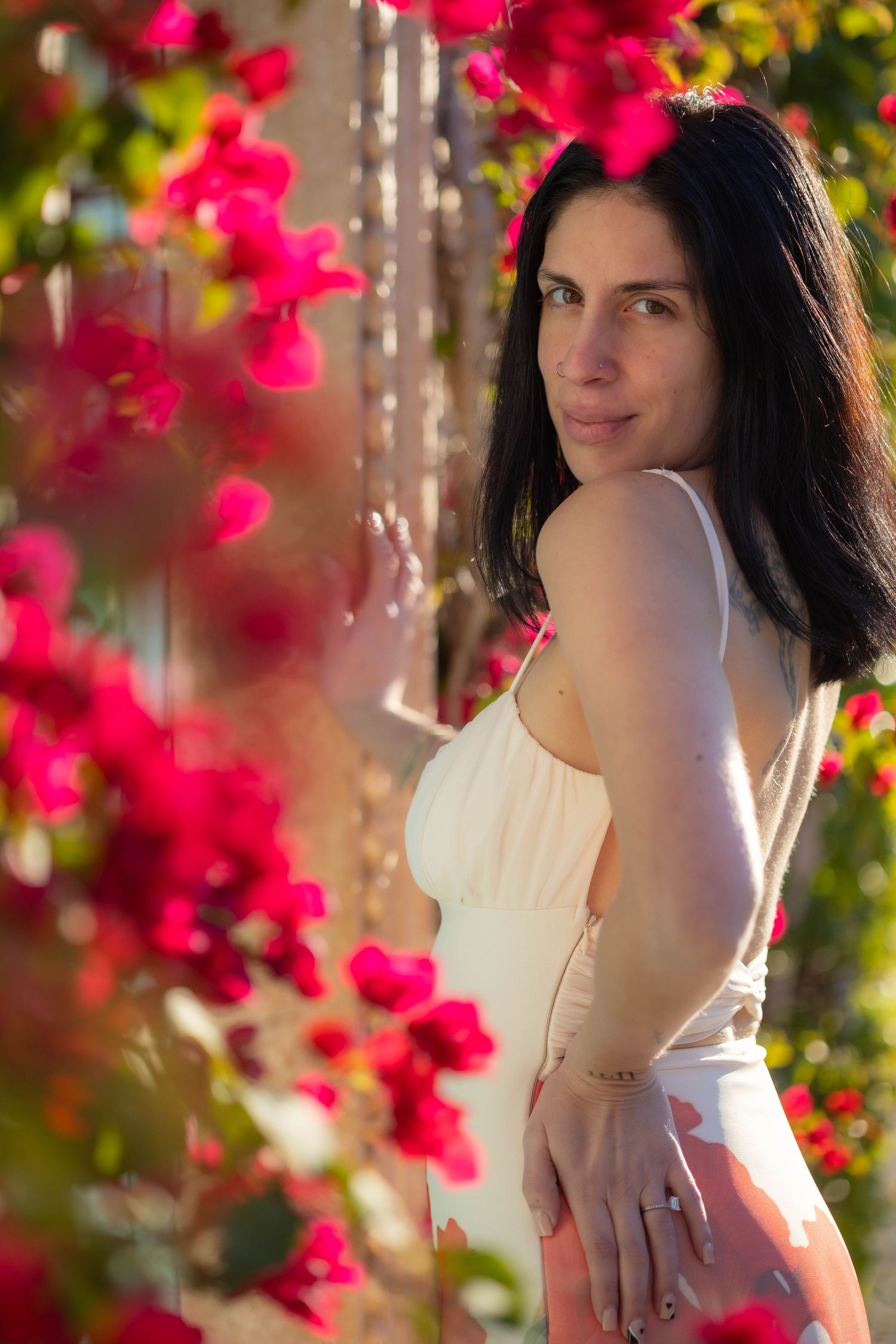 Artistic portrait in a garden with vibrant pink bougainvillea flowers framing the composition.