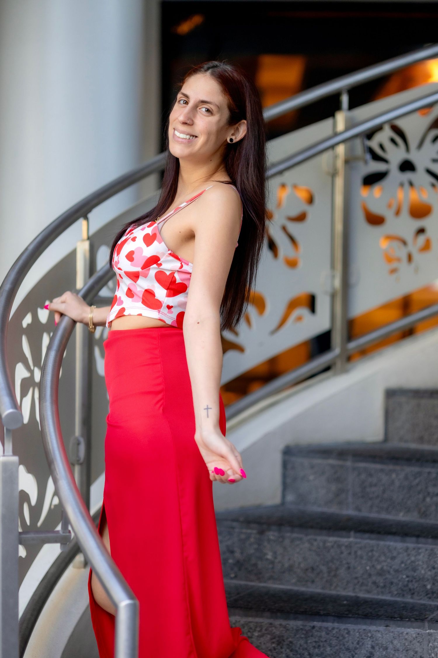 Elegant poses on stairs wearing a flowing red dress with floral details.
