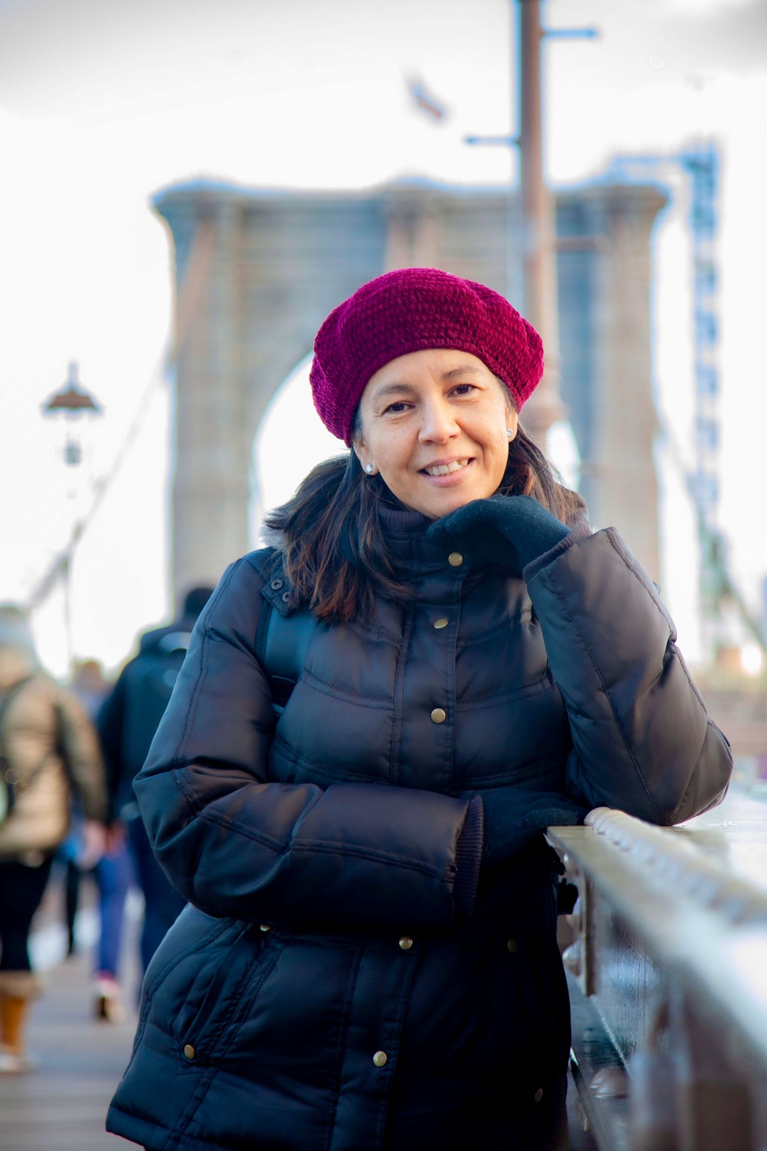 Winter portrait featuring someone in a black puffer jacket and burgundy beanie against an urban backdrop.