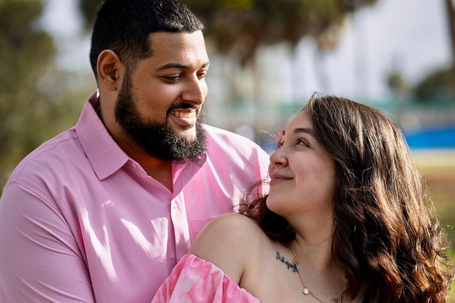 Couple in pink attire sharing intimate moments during outdoor photoshoot.