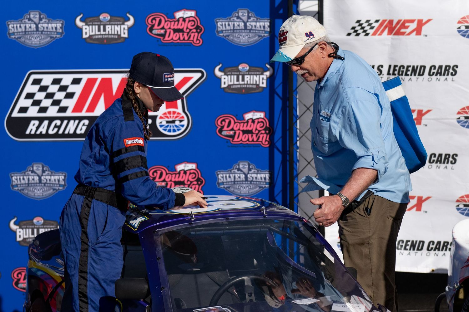 Race driver signs autographs at NASCAR showcasing INEX and US Legends racing