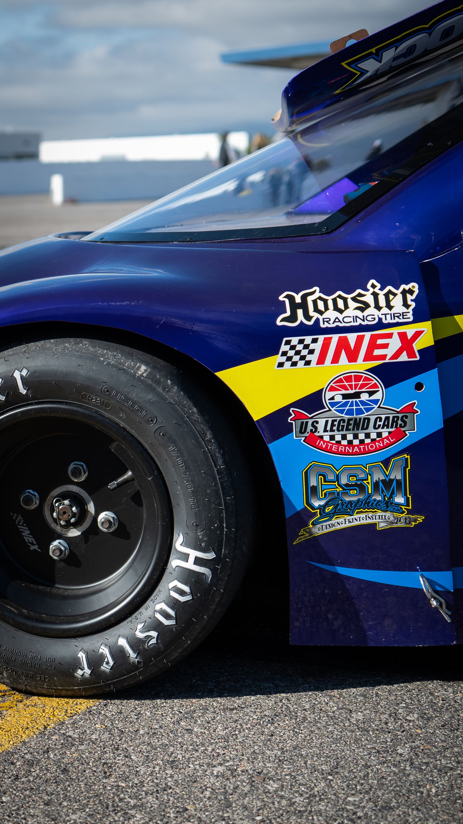 Close-up of blue NASCAR Legend Car featuring Hoosier, INEX, and US Legend Cars International sponsors.