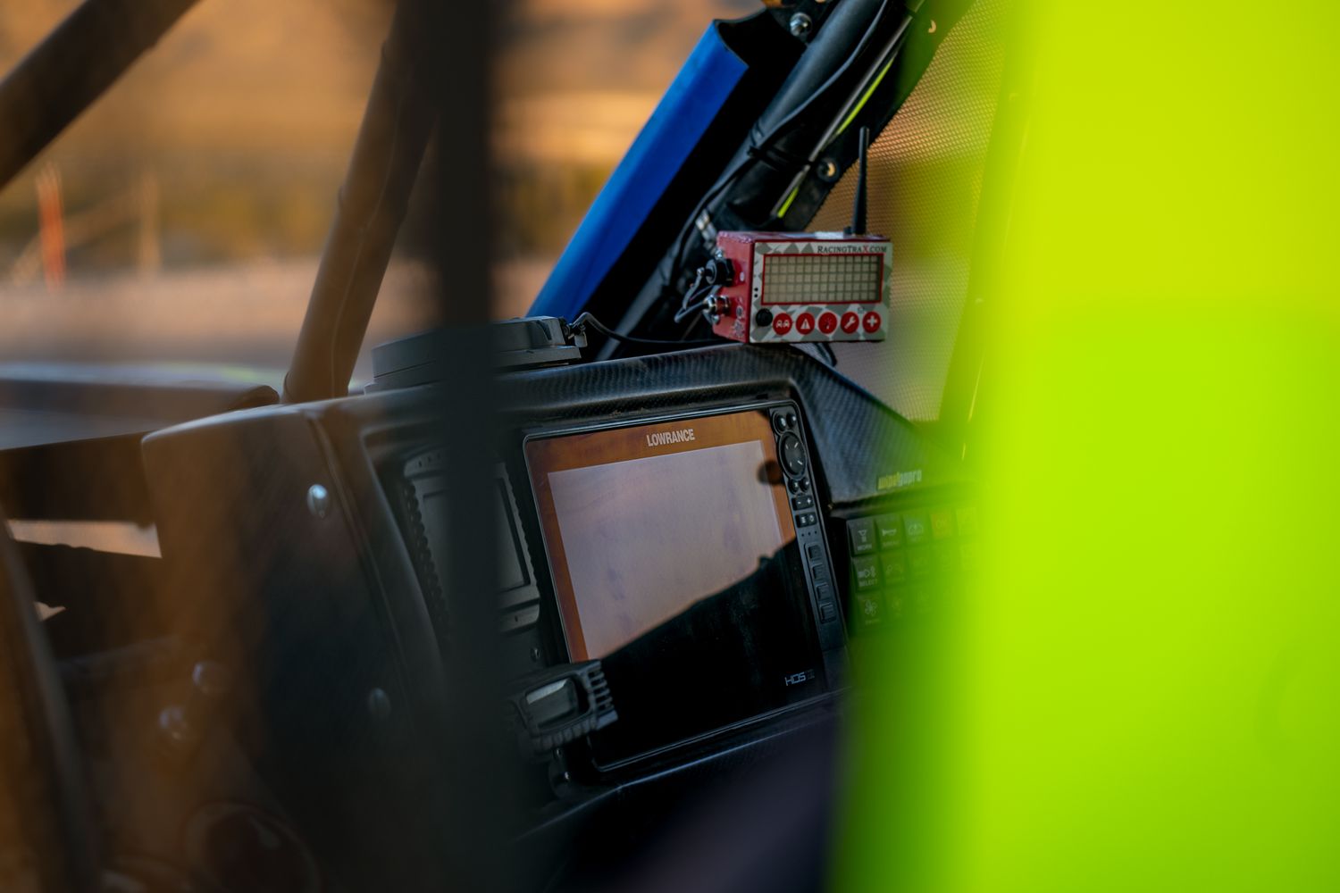 Interior cockpit view of off-road trophy truck showing navigation display and race equipment through roll cage.