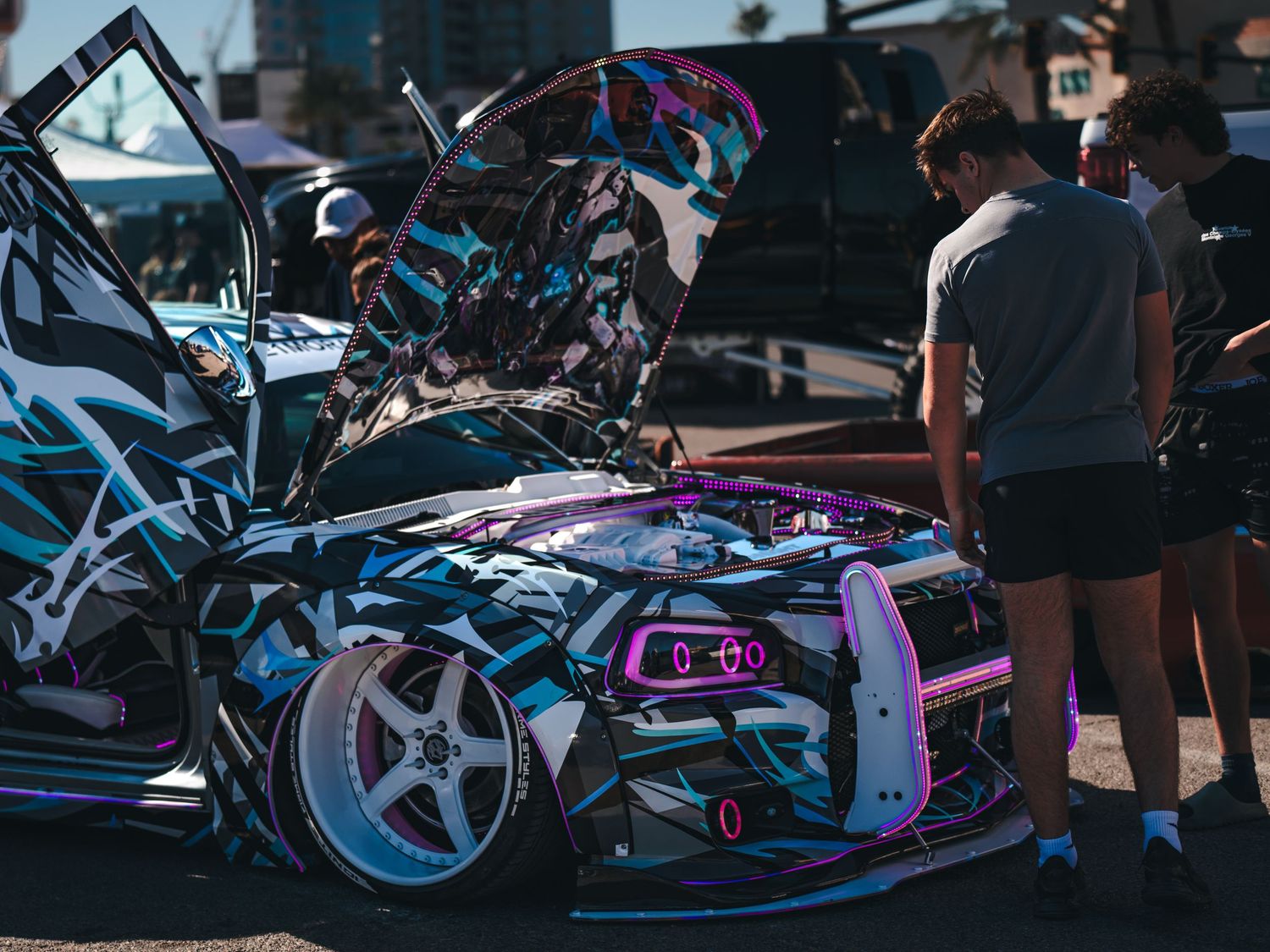 Young man admiring a wildly customized anime-themed drift car with colorful wrap at Super Saturday Weekend at The STRAT in Las Vegas