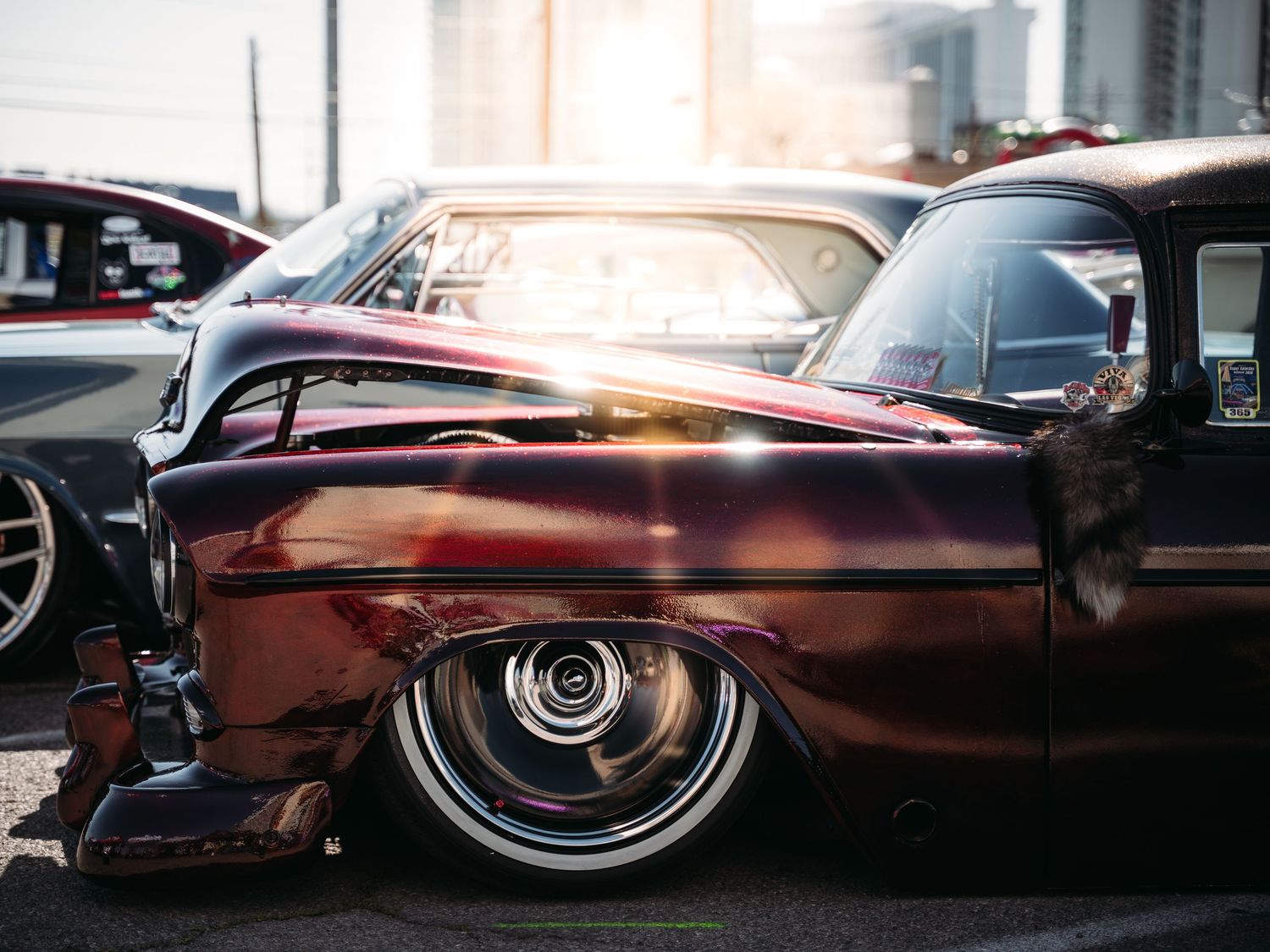 Deep burgundy lowrider classic car with custom chrome wheels gleaming in sunlight at Super Saturday Weekend at The STRAT in Las Vegas