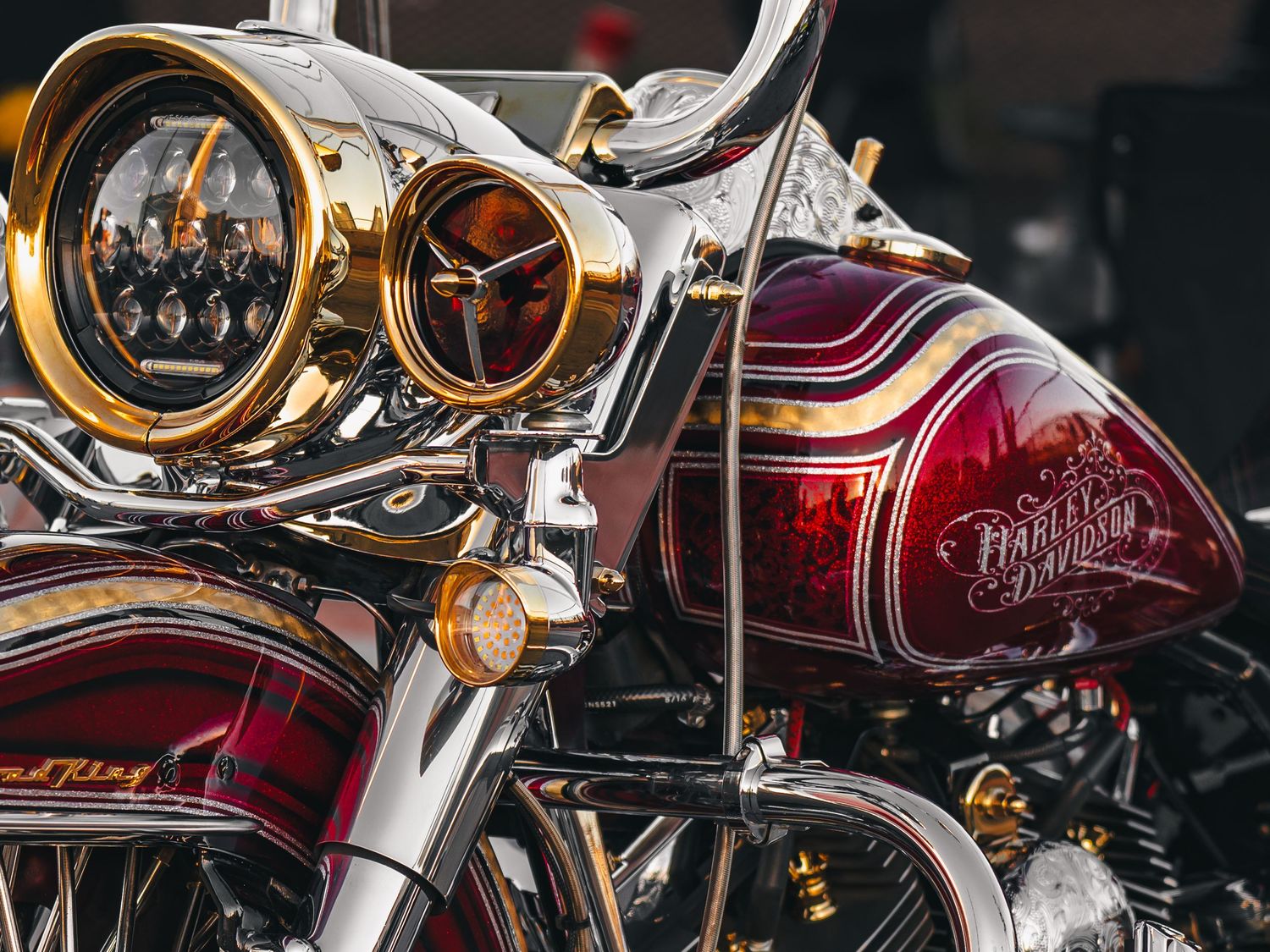 Close-up of a heavily customized burgundy and gold Harley-Davidson motorcycle with ornate details.
