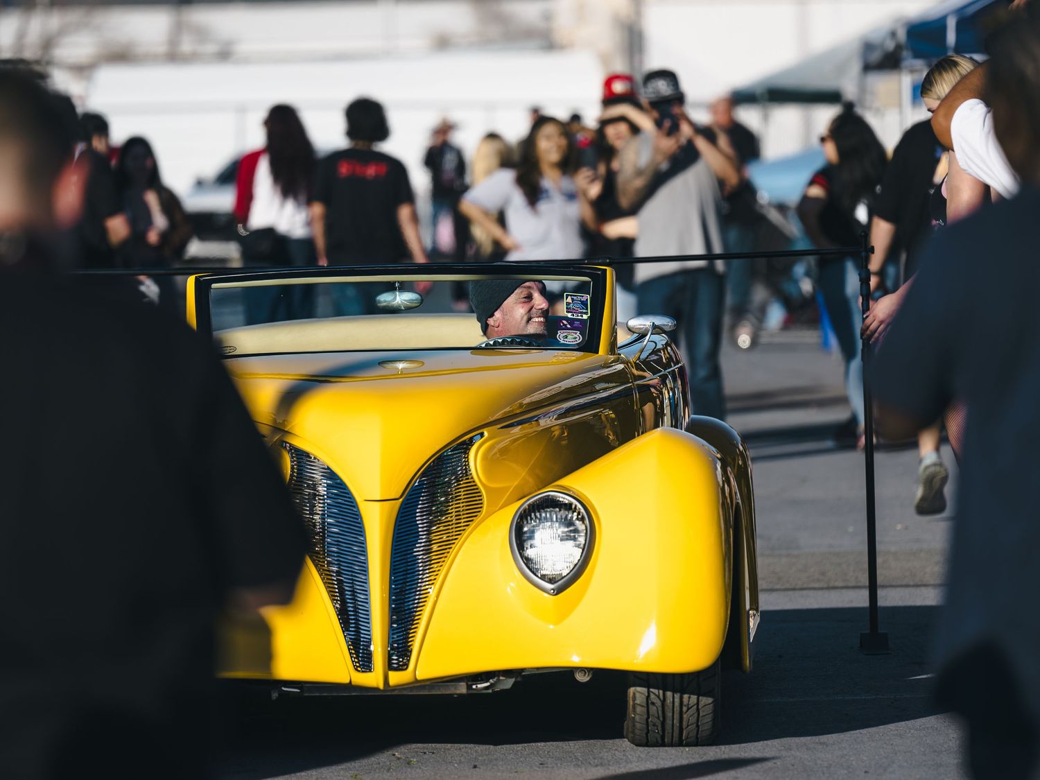 Bright yellow vintage custom hot rod convertible cruising past crowd at Super Saturday Weekend at The STRAT in Las Vegas