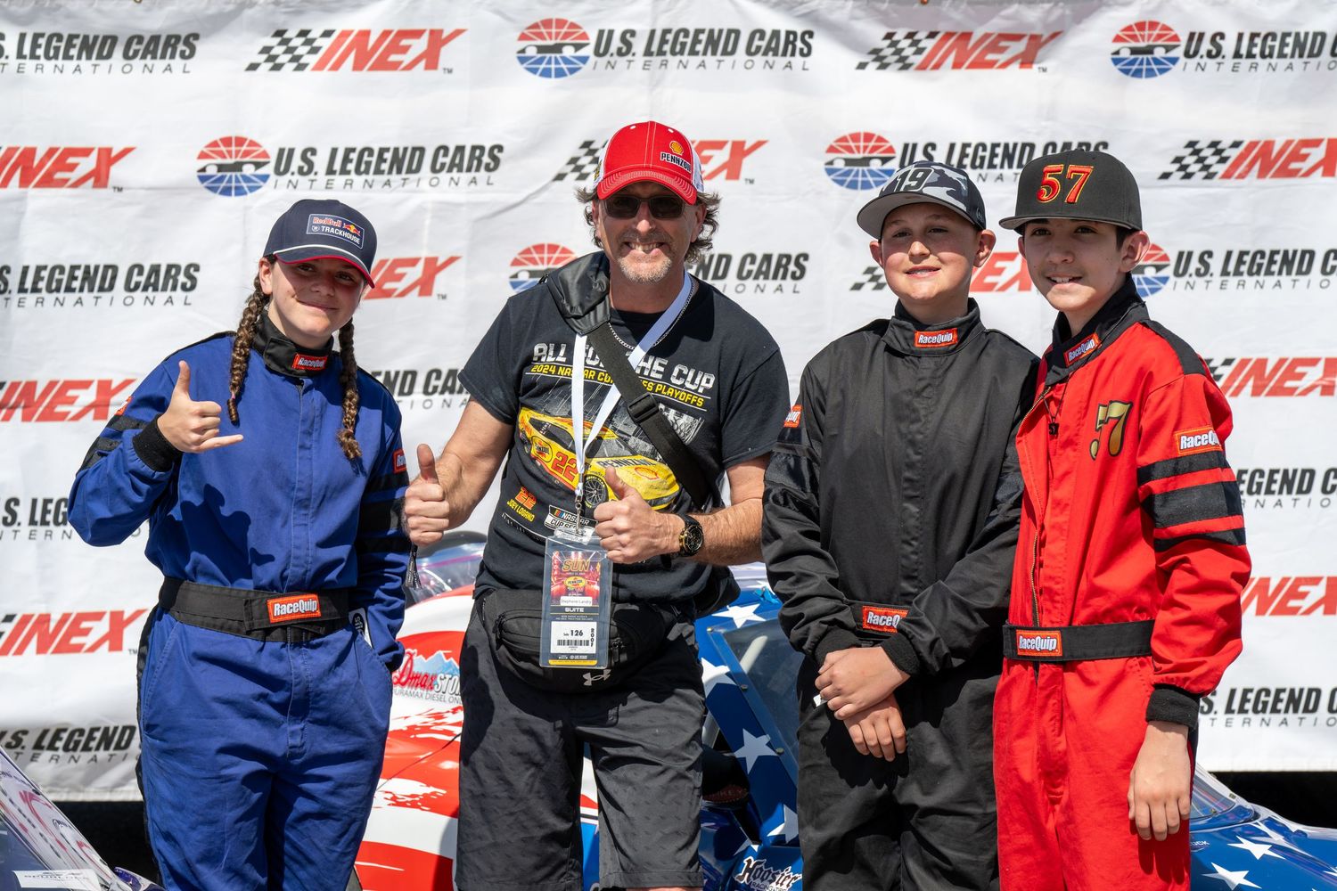 Four people pose together for a victory photo at NASCAR showcasing for US Legend Cars INEX racing