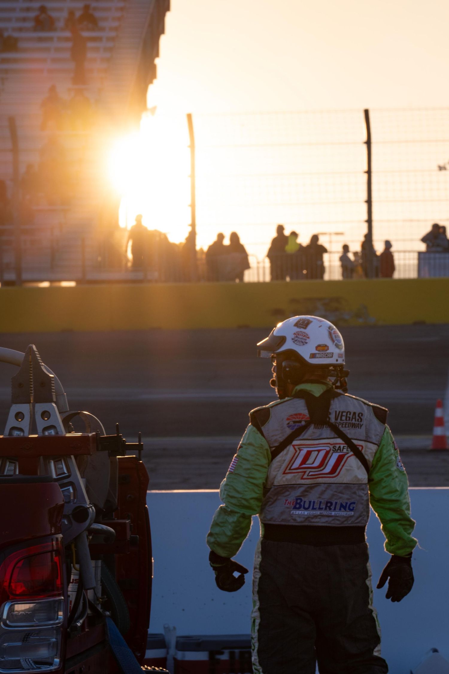 Recovery crew in green firesuit in pit lane at sunset during Las Vegas race event.