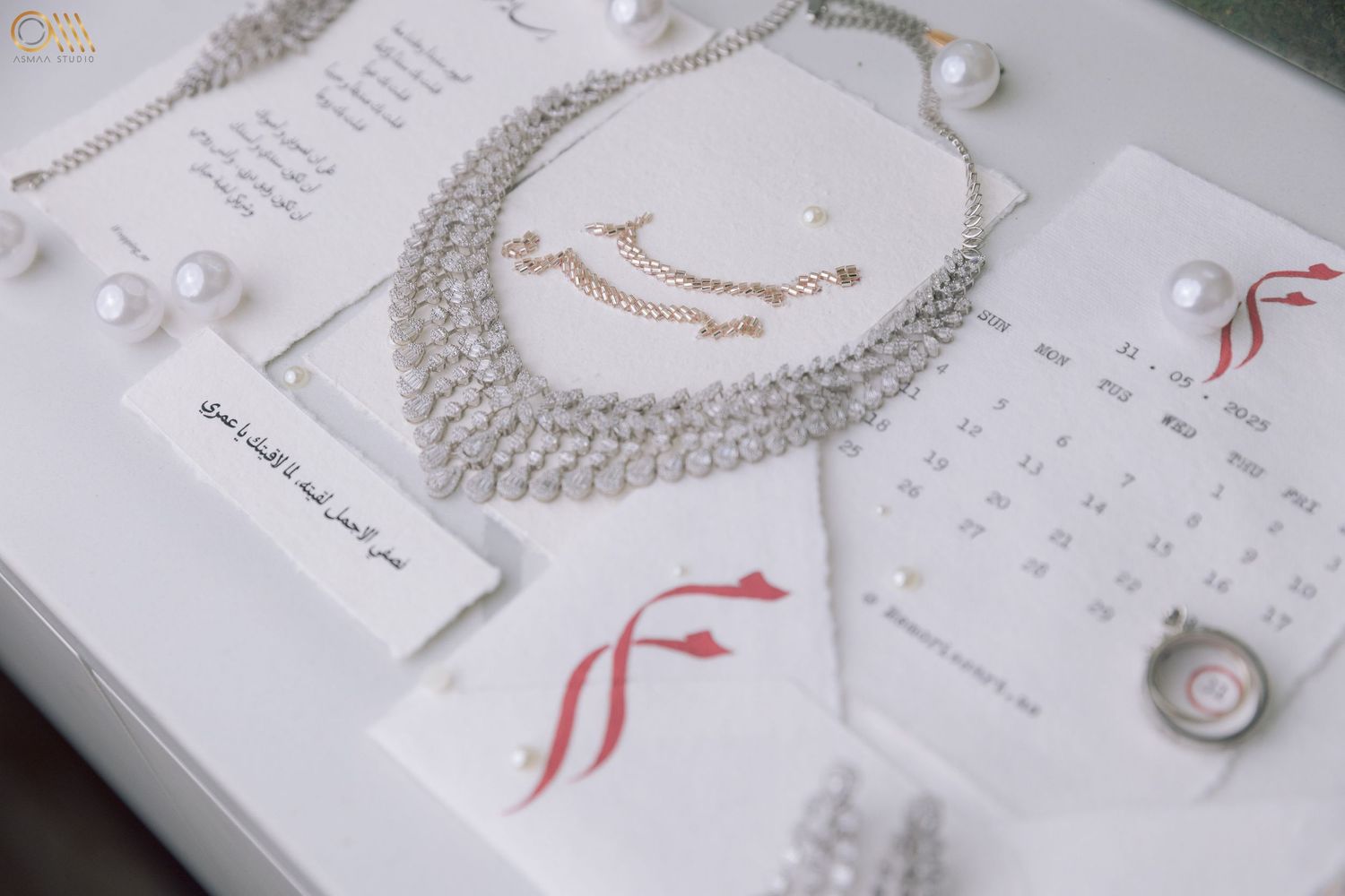 Pearl necklaces and wedding stationery arranged artistically with red accents.