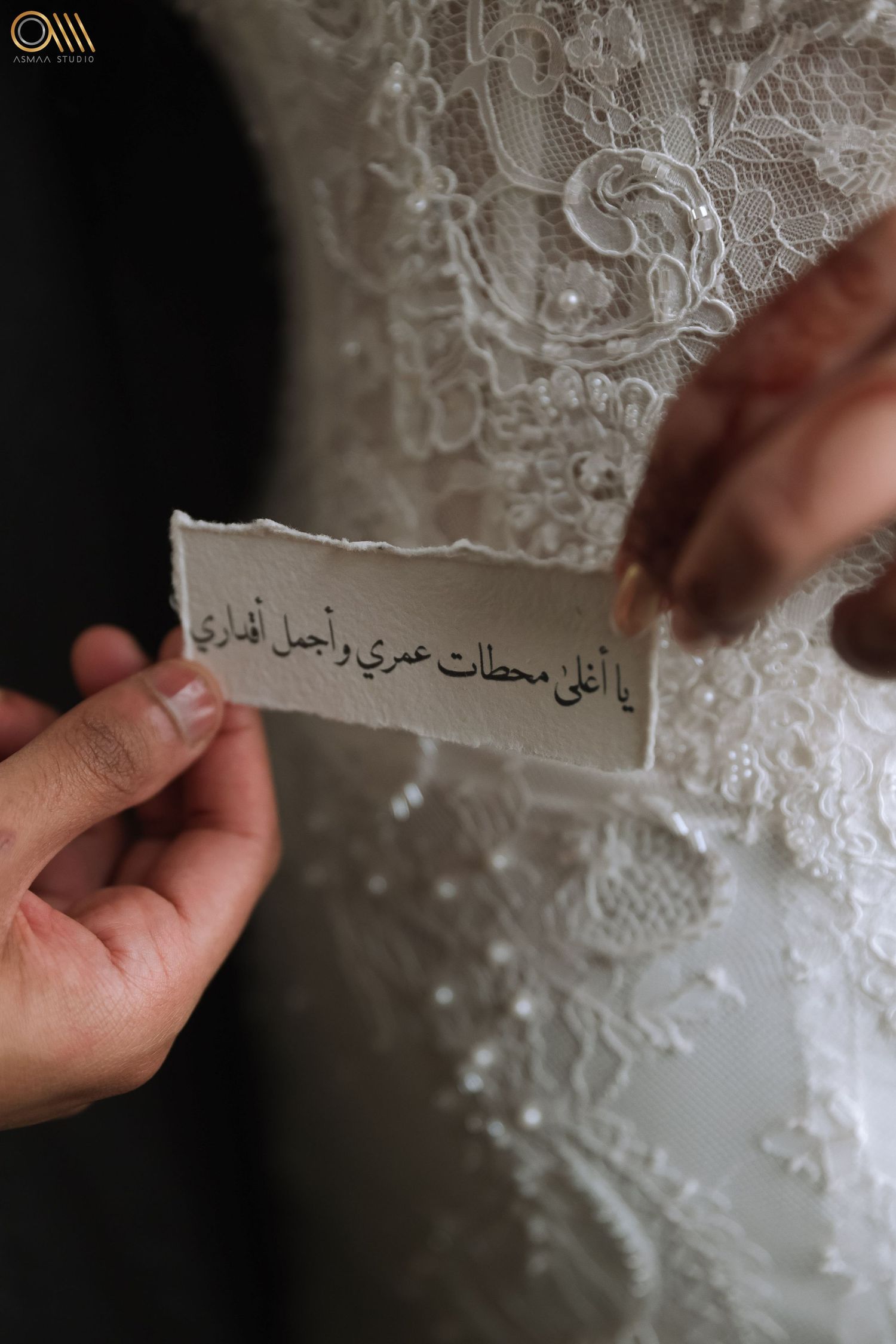 Arabic calligraphy embroidered on delicate white lace wedding dress fabric.