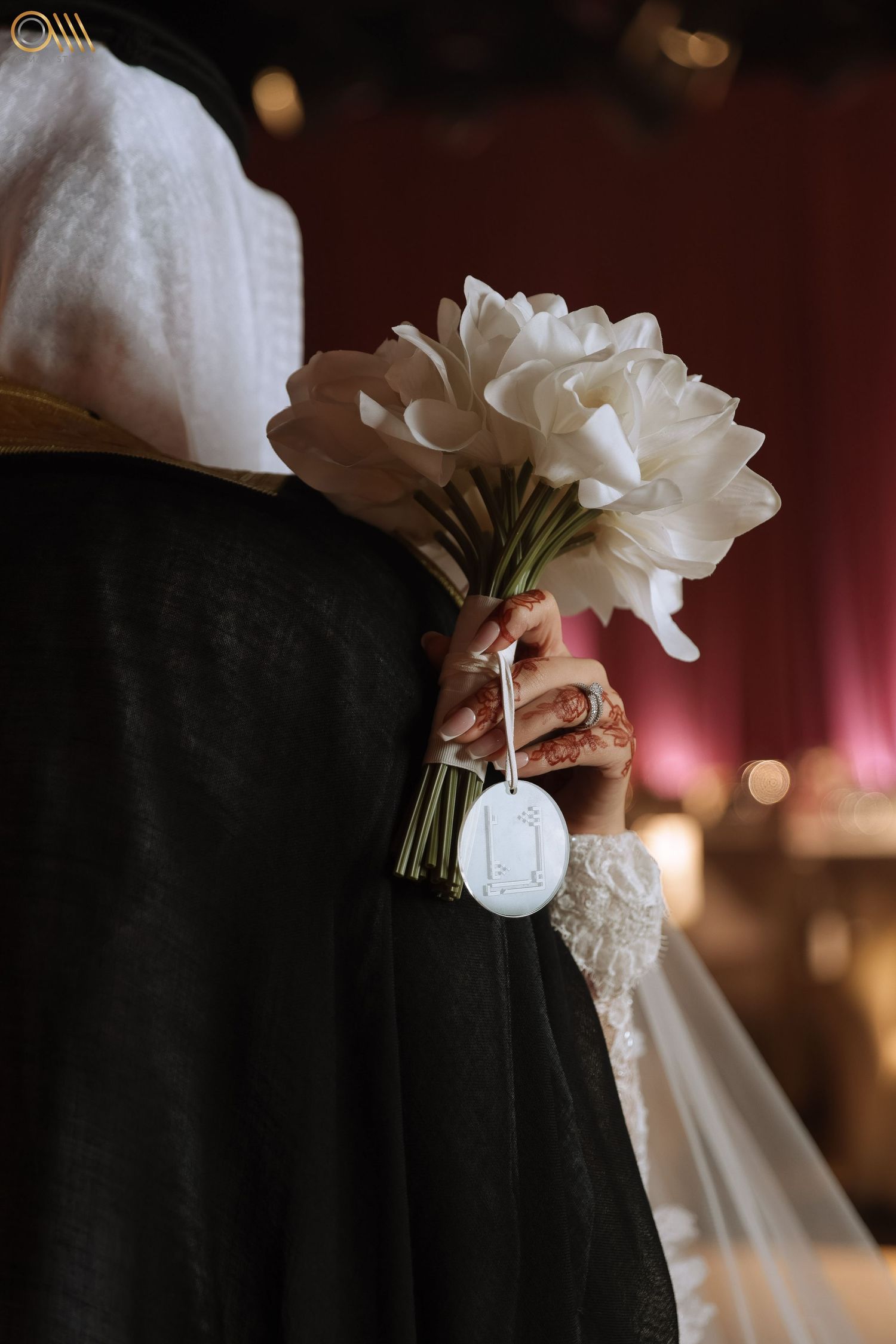 White bridal bouquet being held against a dark background with soft bokeh lighting.