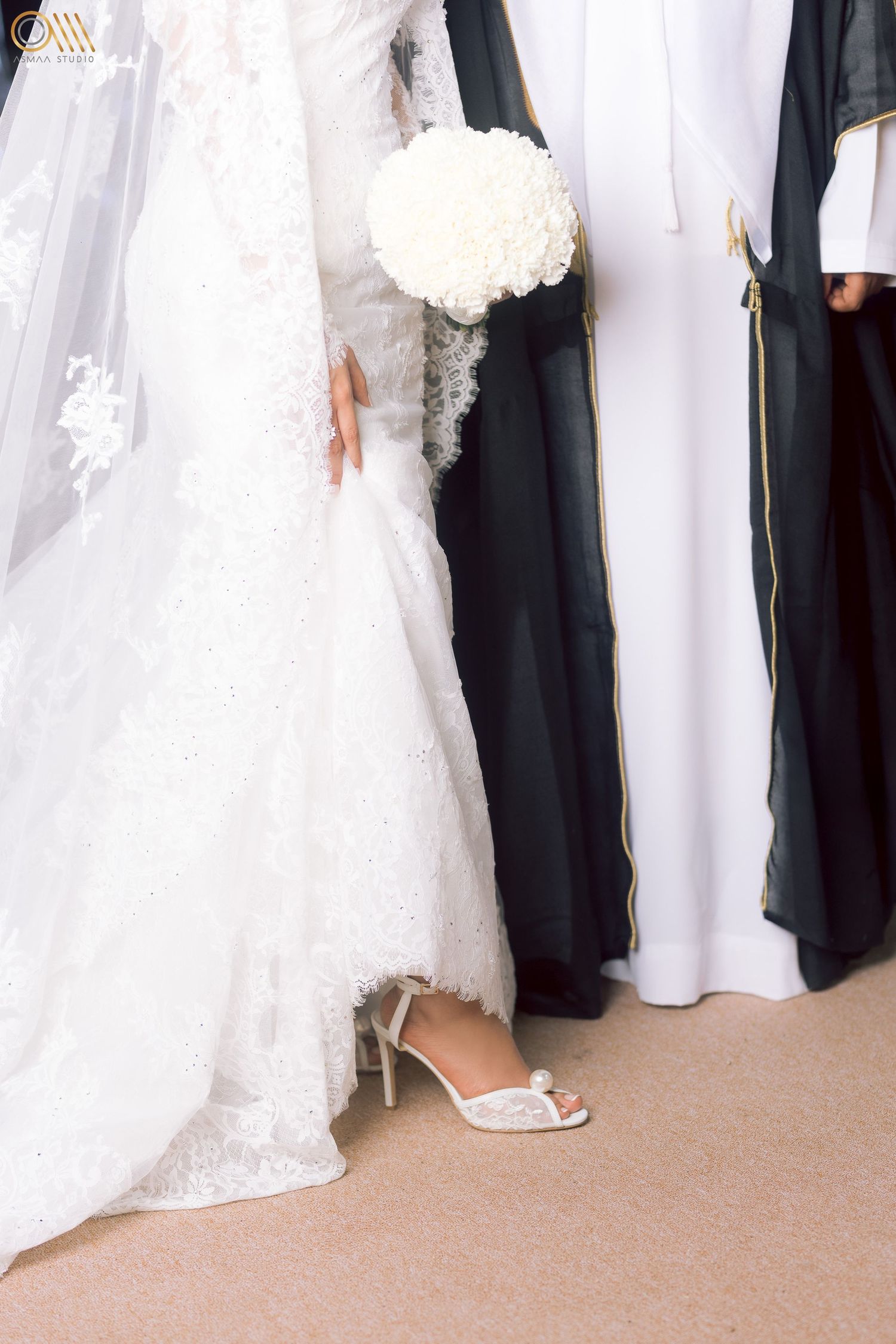 Detail shot of traditional Middle Eastern wedding attire showing white dresses and black bishts.
