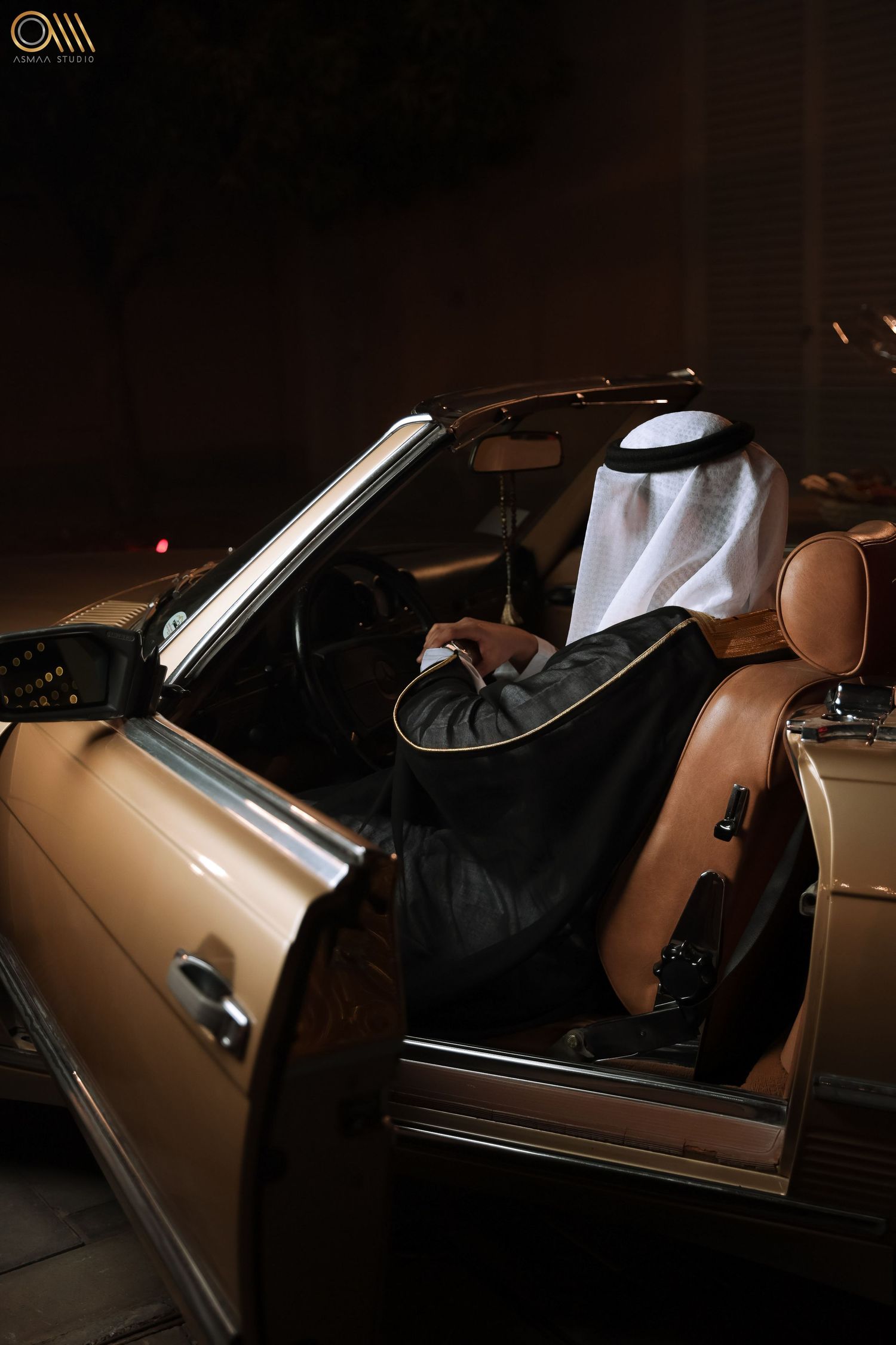 Person in traditional Middle Eastern attire entering a luxury gold-colored car.