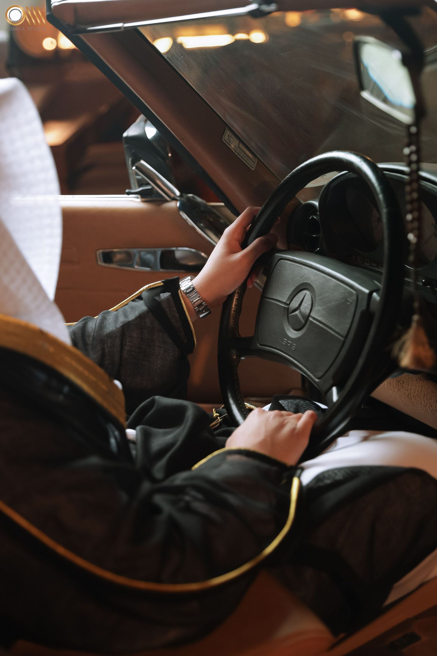 Close-up of hands on Mercedes-Benz steering wheel in luxury car interior.