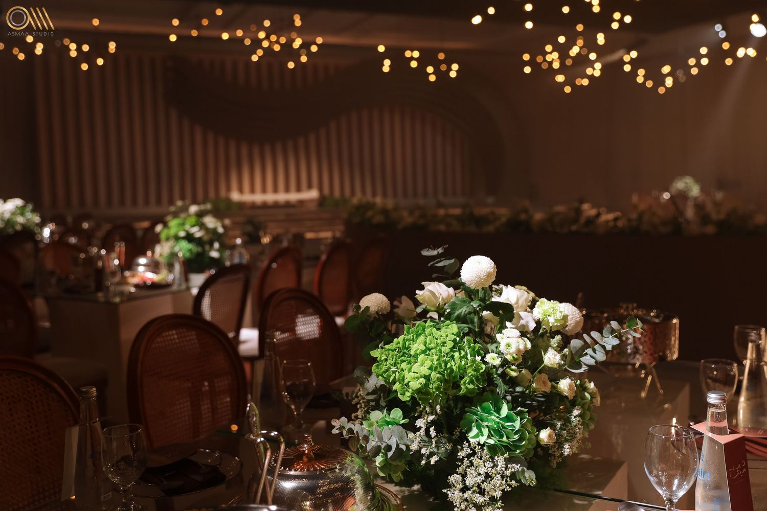 Wedding reception venue decorated with warm lighting and elegant table settings.