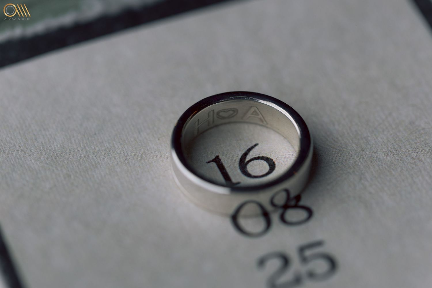 Wedding date numbers and rings photographed on a light gray surface.