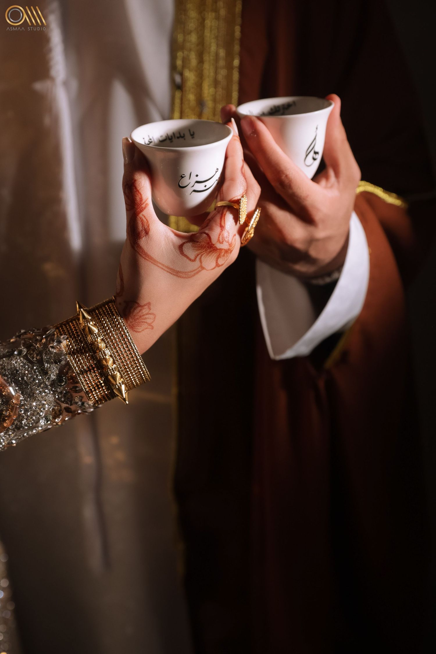 Two decorated Arabic coffee cups held in elegant celebration setting.
