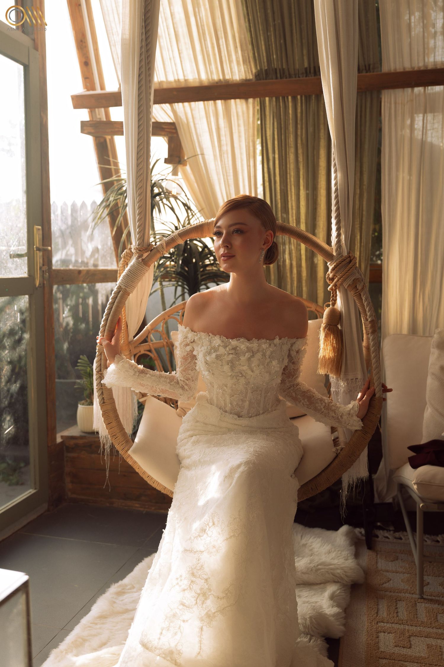 Sunlit indoor bridal portraits showcasing an ornate wedding dress in a room with flowing curtains.