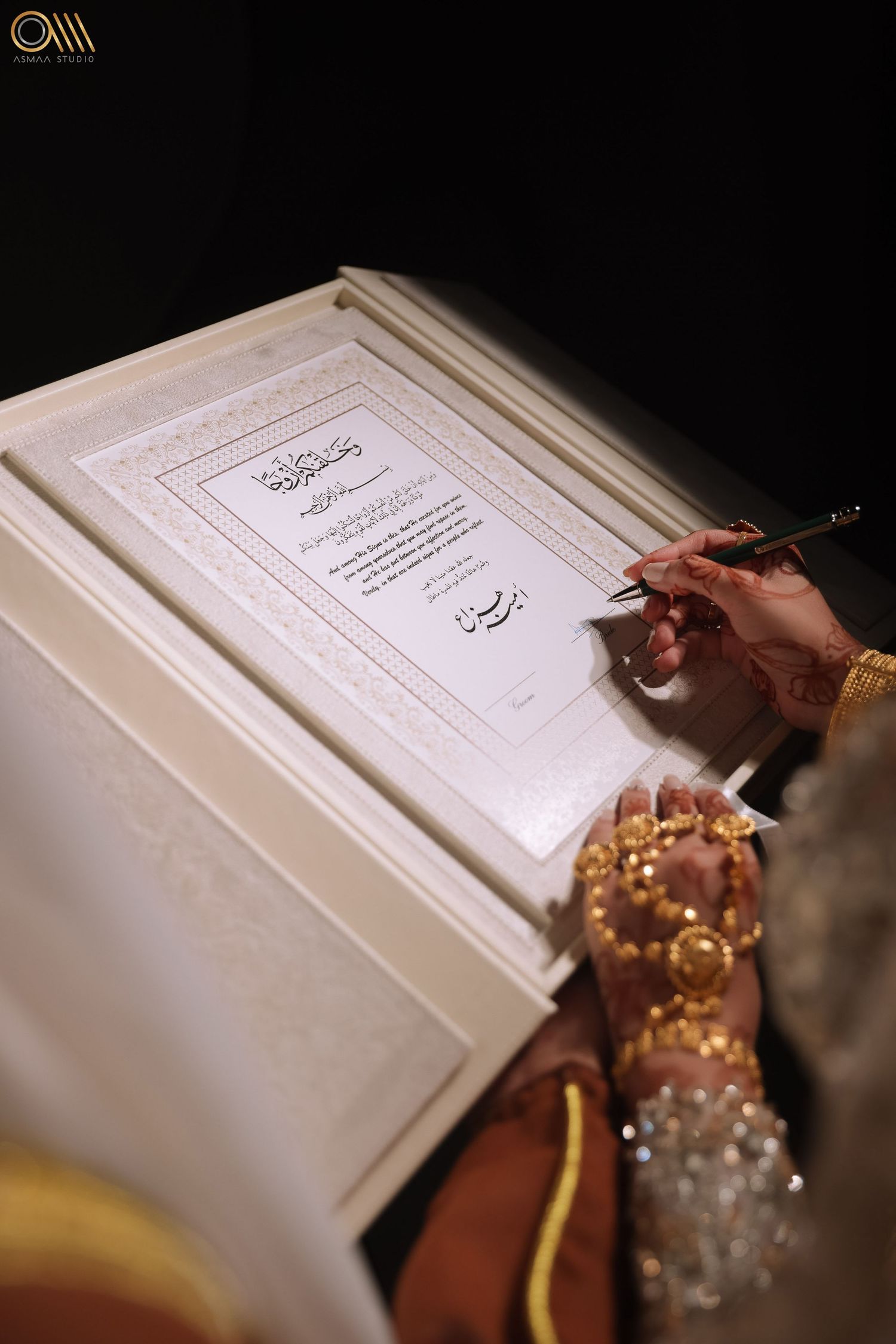 Person wearing traditional jewelry signing an official document on white paper.