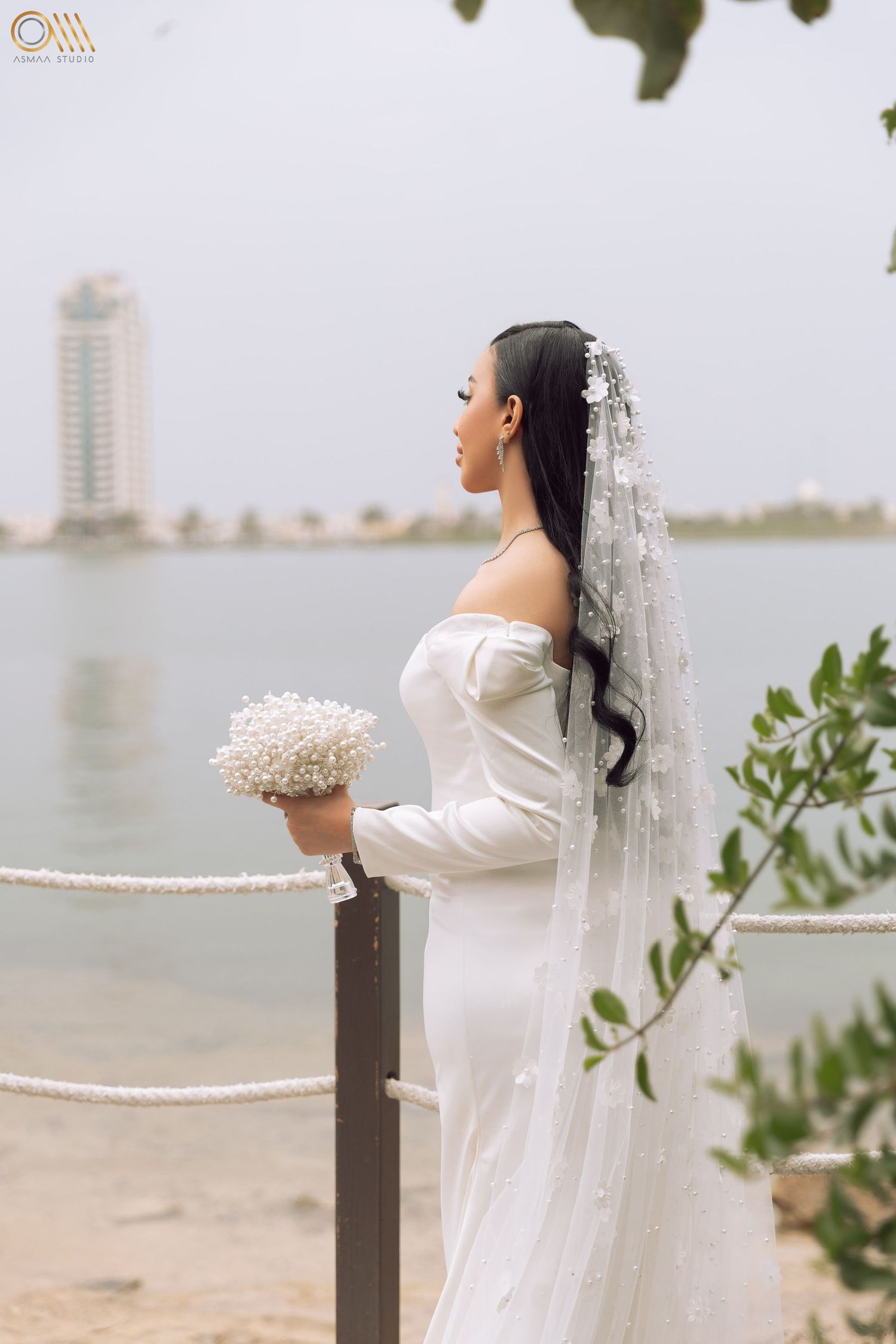Seaside bridal portraits with a white dress and veil against a coastal background.
