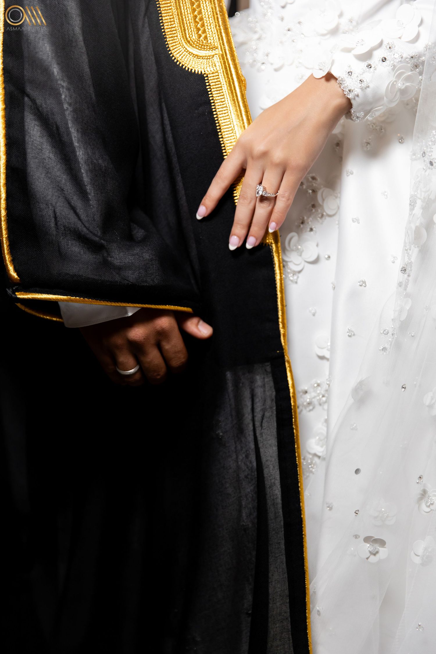Contrast of black bisht with gold trim against white wedding dress.