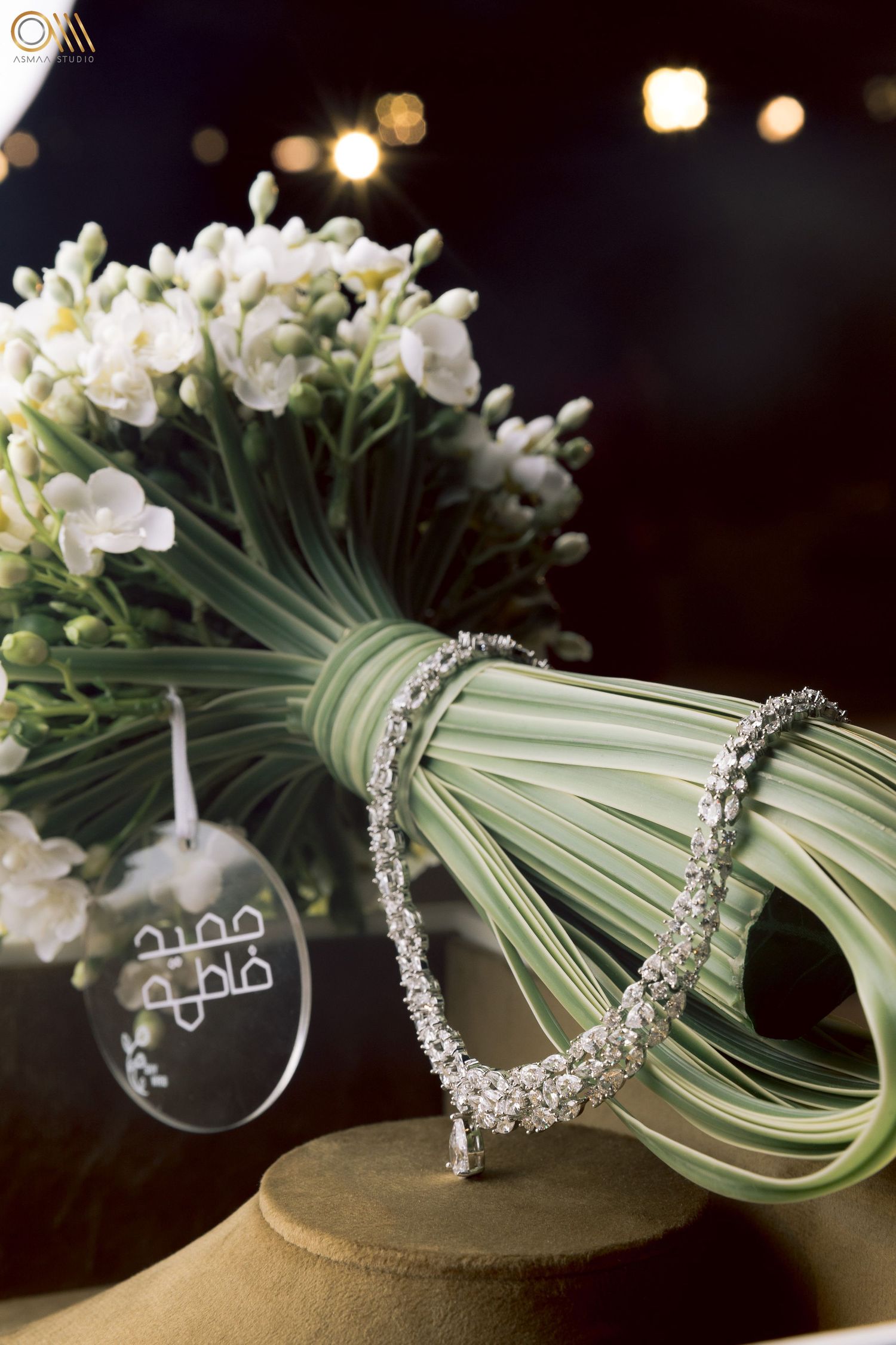 Crystal necklace displayed with white flowers and palm leaves in elegant wedding styling.