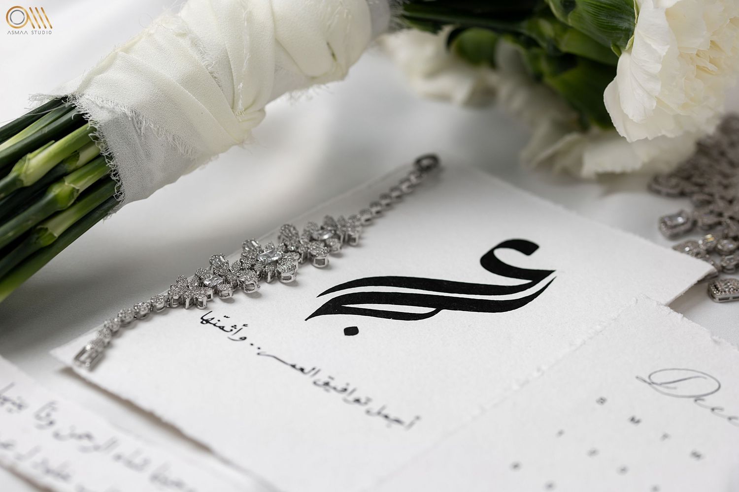 White floral arrangements and elegant stationery with delicate pearl accents on a light background.